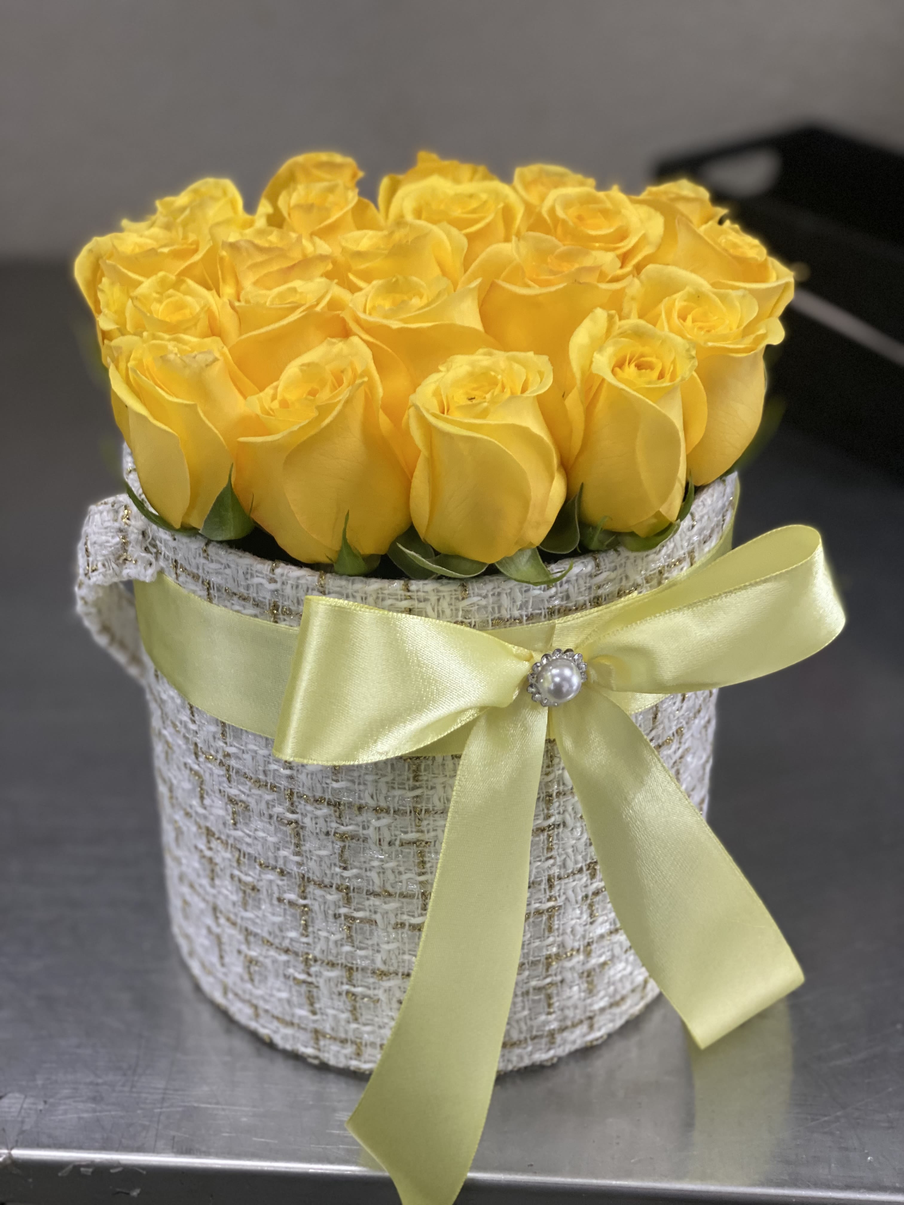 Yellow roses arranged in a round hatbox with a satin ribbon
