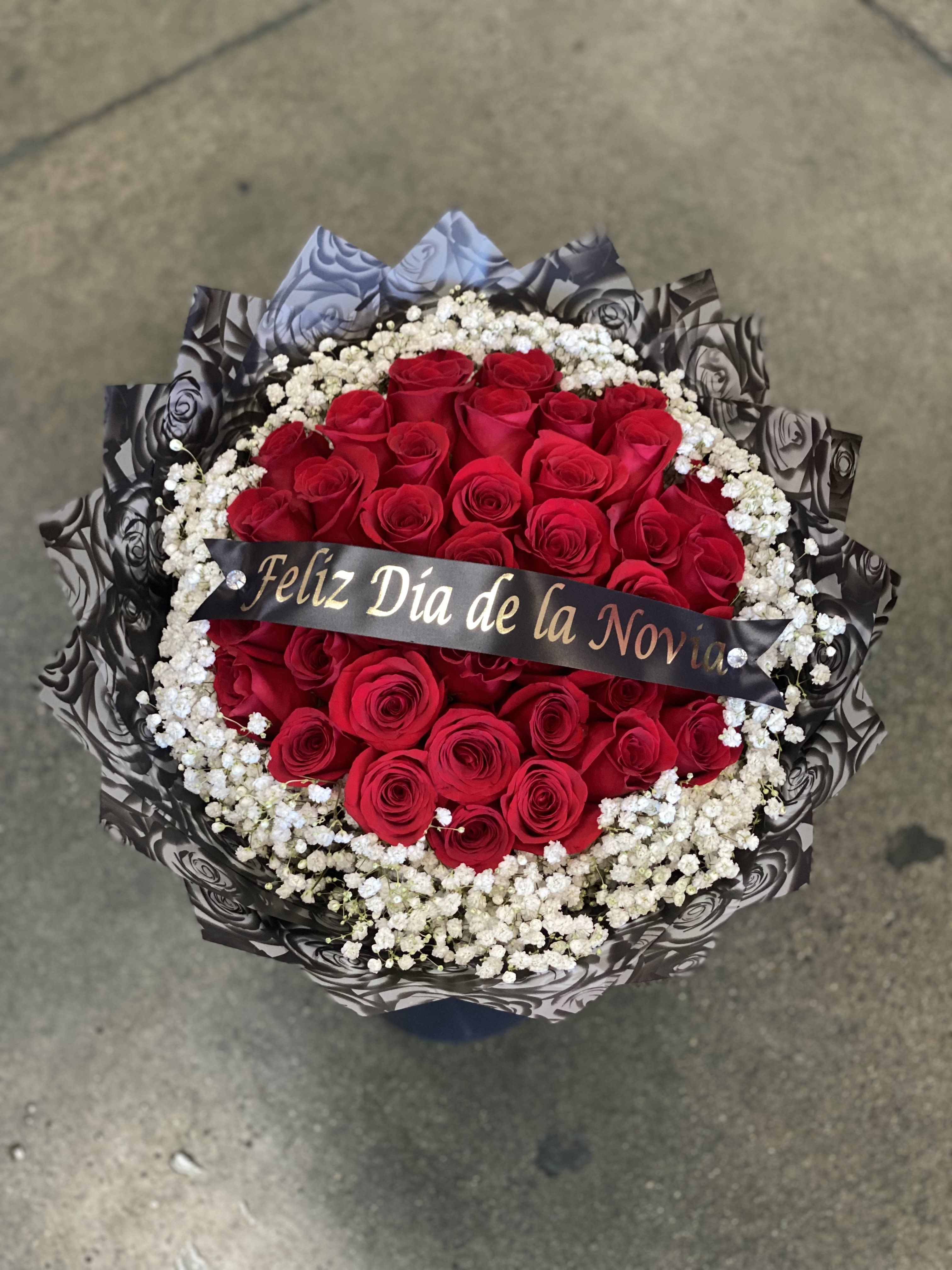 Round bouquet of red roses with white baby's breath and a ribbon
