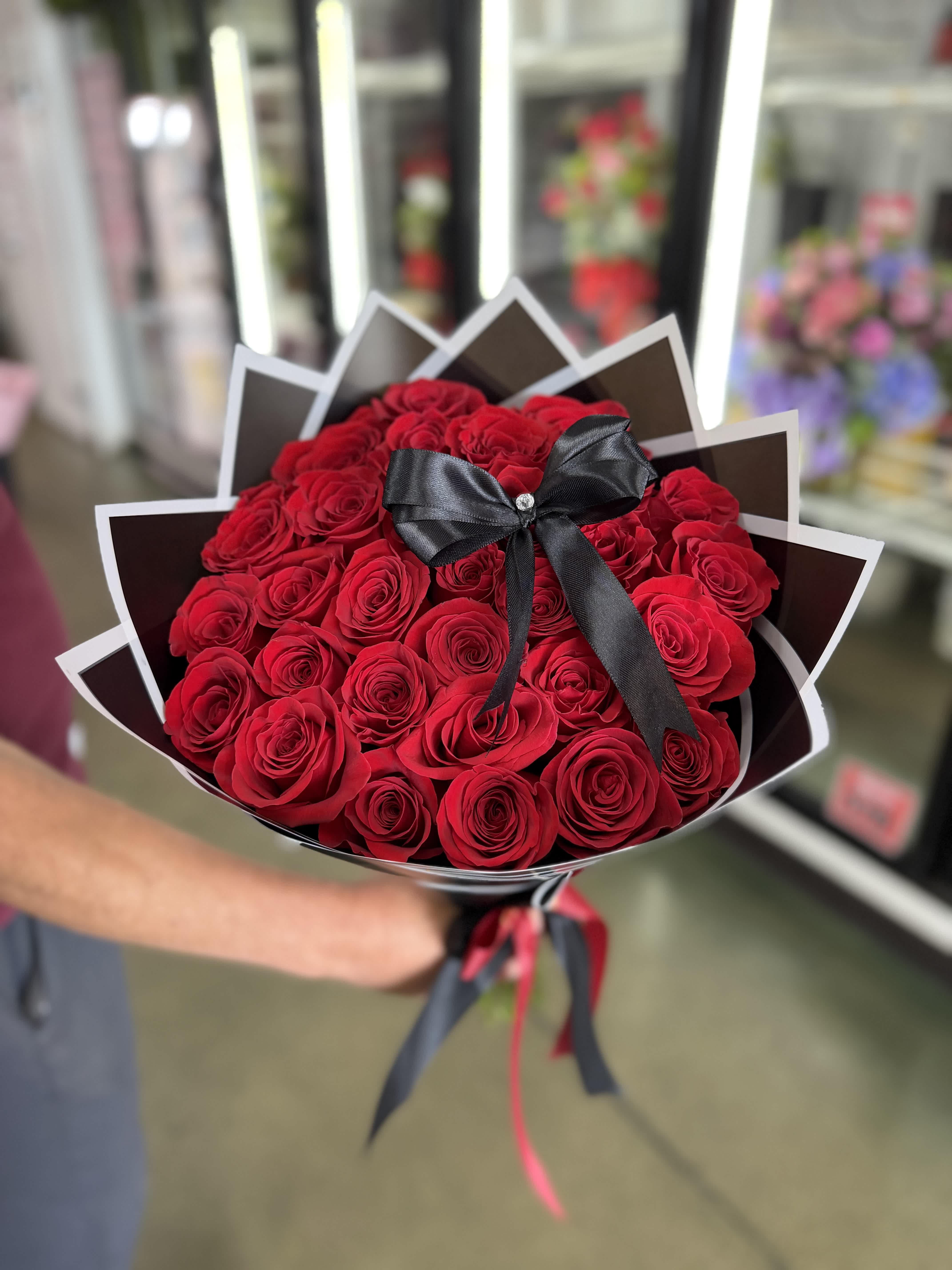 Bouquet of red roses wrapped in black paper with a black ribbon