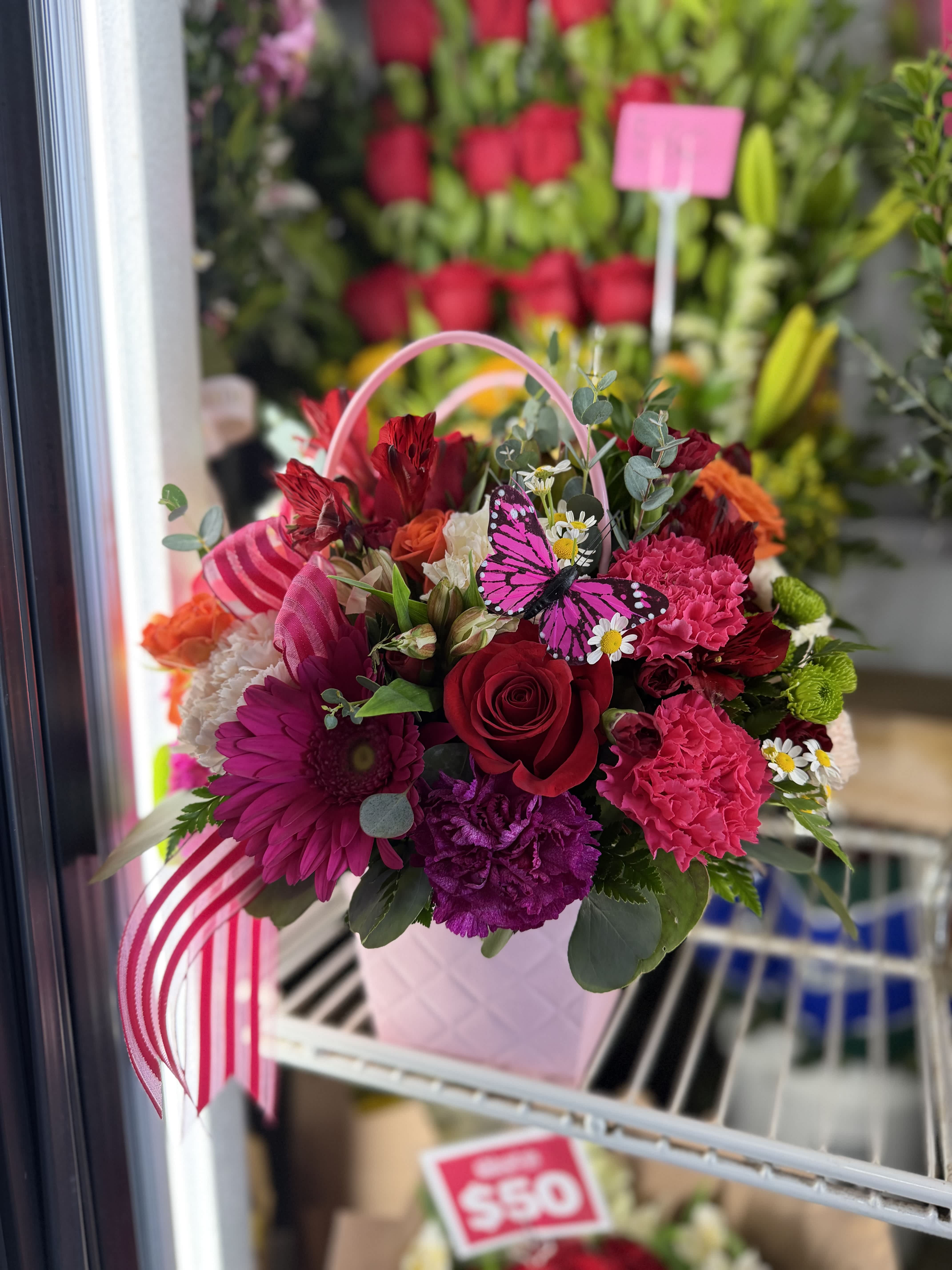 Pink and red mixed flower basket with a butterfly decoration