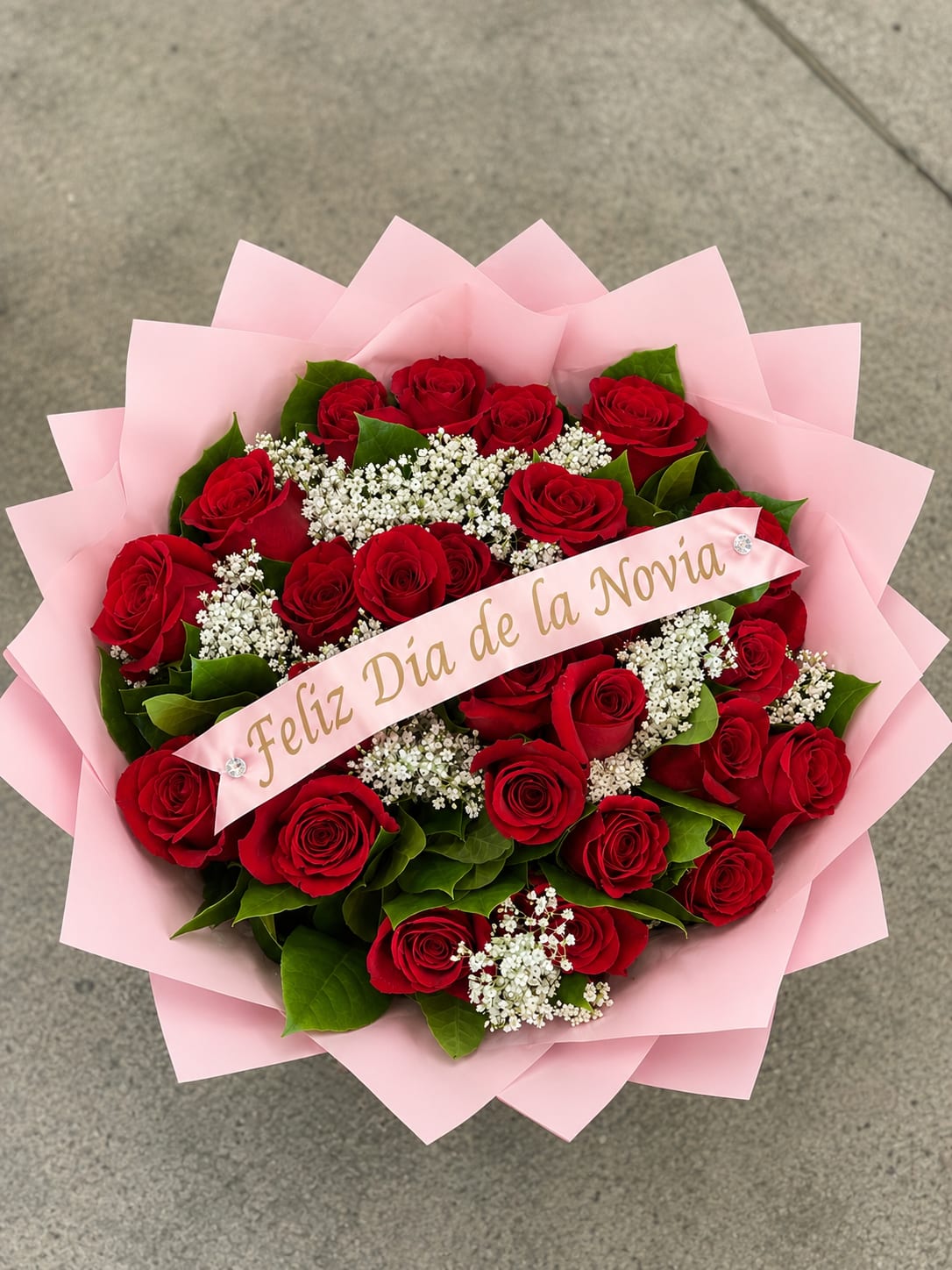 Bouquet of red roses with white filler flowers wrapped in pink paper