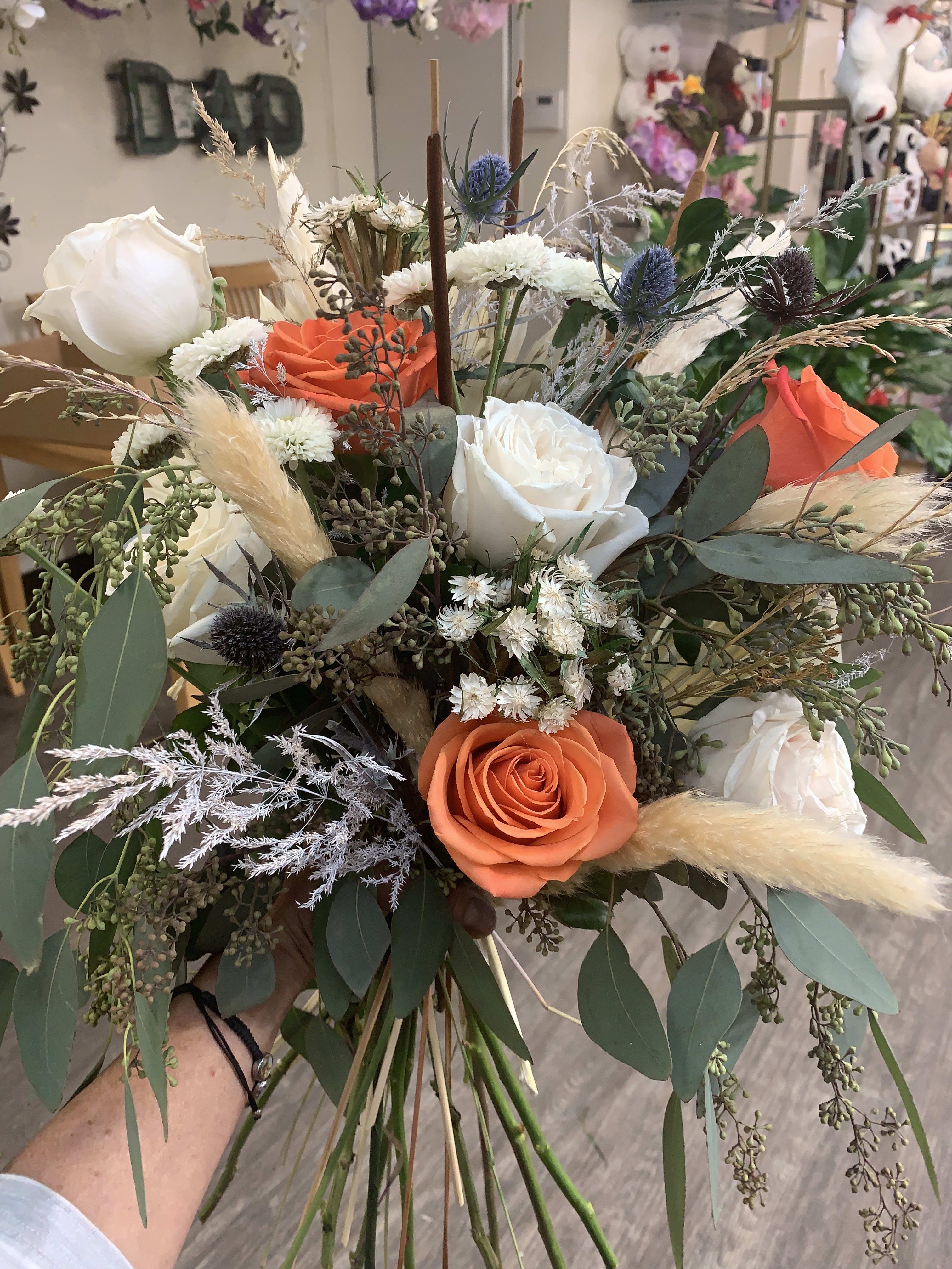 Hand-tied bouquet of orange and white roses with dried grasses
