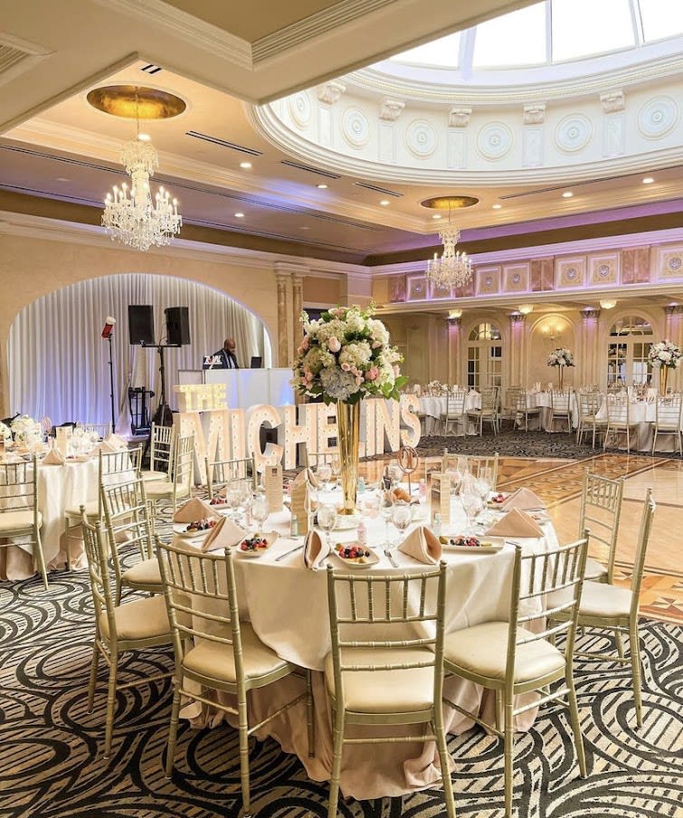 Floral centerpieces on round banquet tables in a decorated ballroom