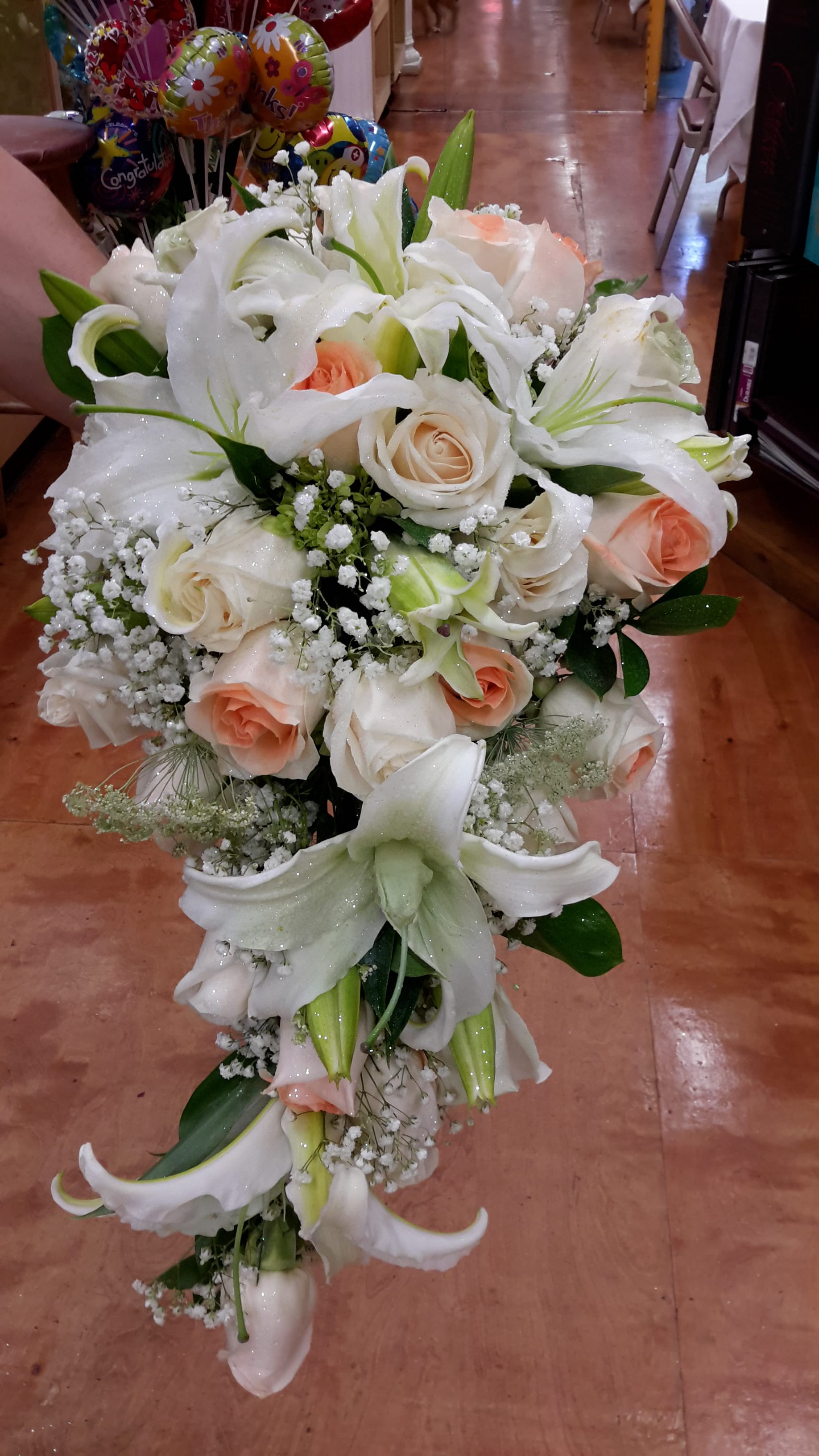 Cascade bouquet of white lilies and peach roses with baby's breath