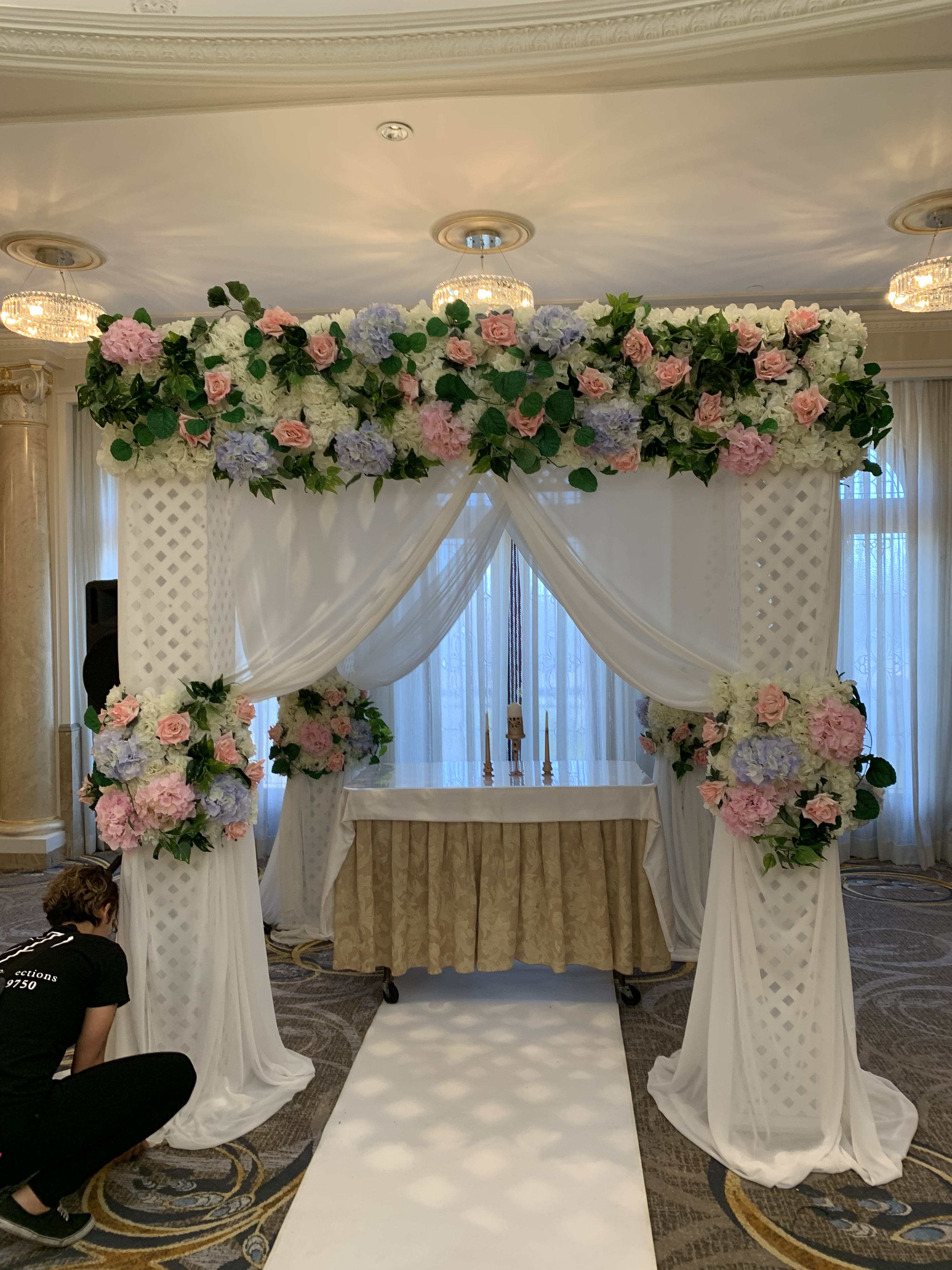 Wedding altar with pink and white floral arrangements and draped fabric
