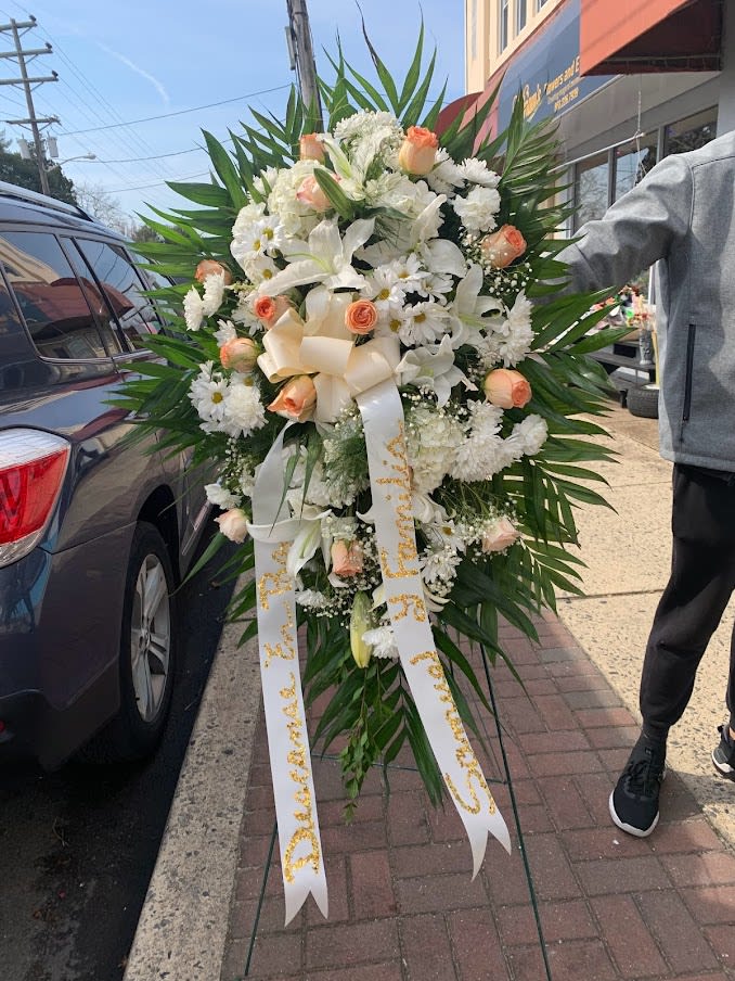 Large standing floral spray with white flowers and peach roses on an easel