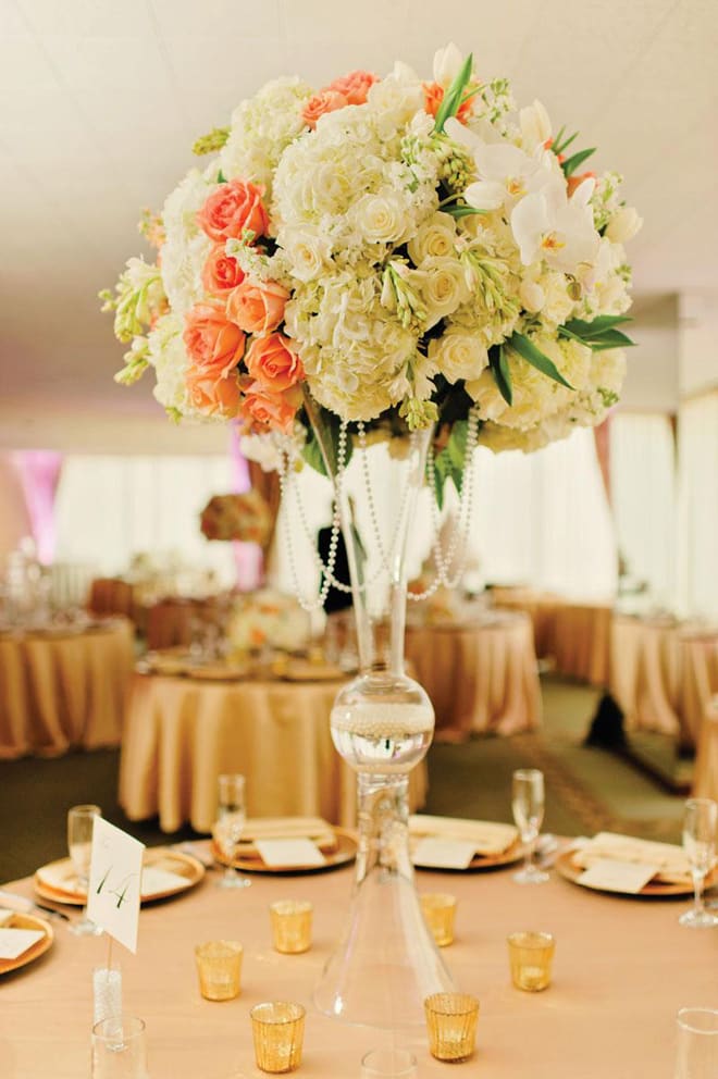 Tall floral centerpiece with white and peach blooms in a clear glass vase
