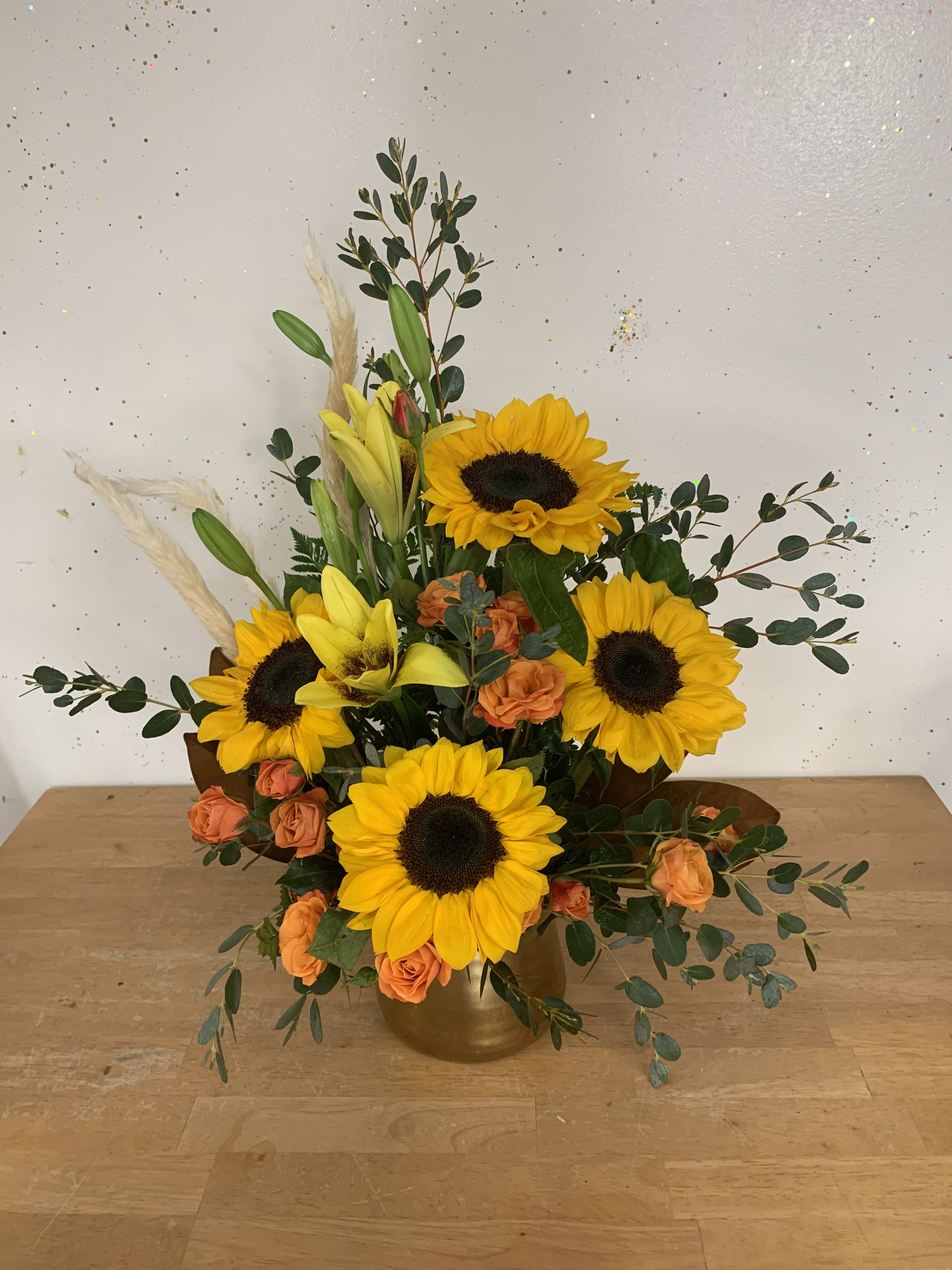 Sunflower and orange rose arrangement in a gold vase