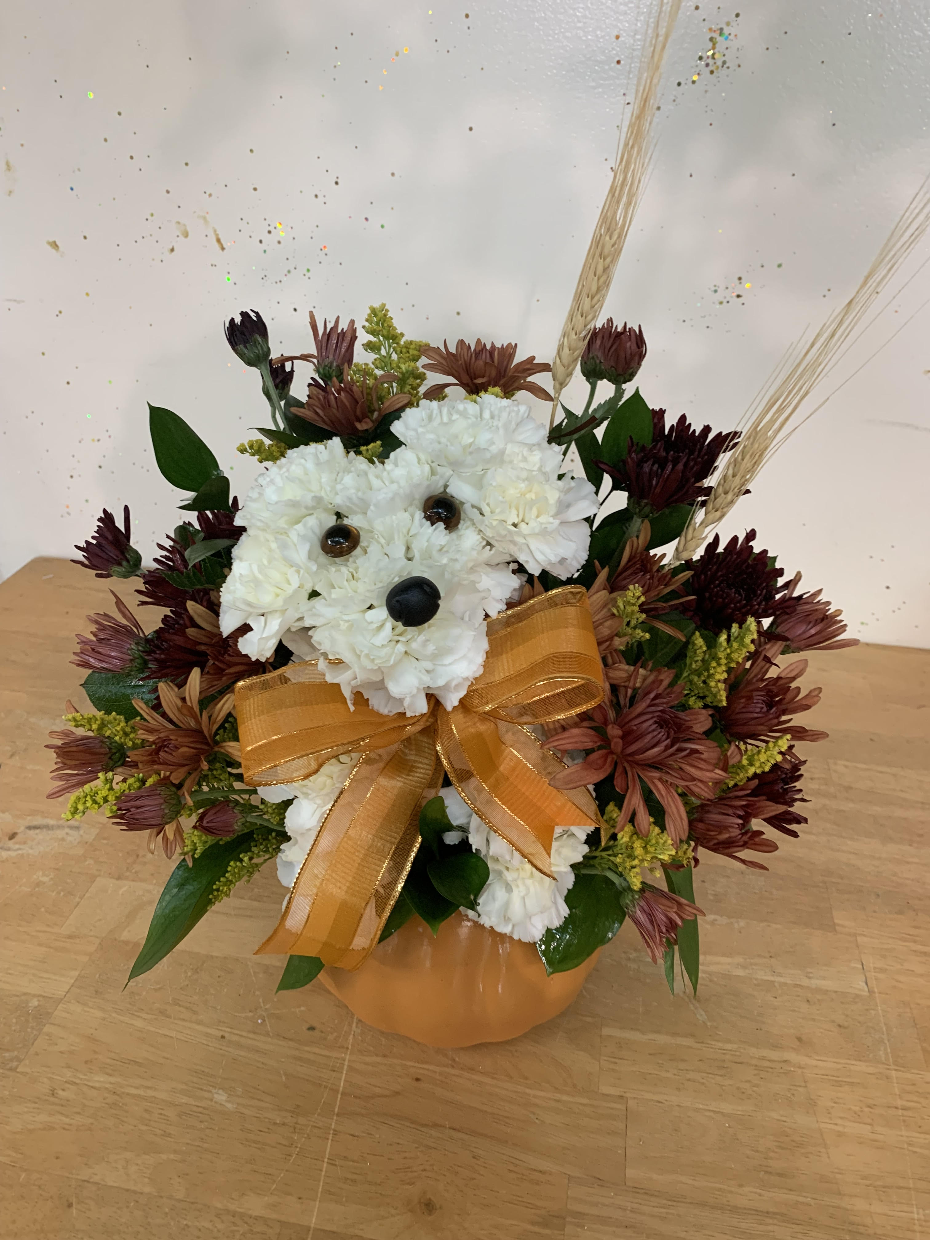White flower bear arrangement with an orange bow in a pumpkin vase