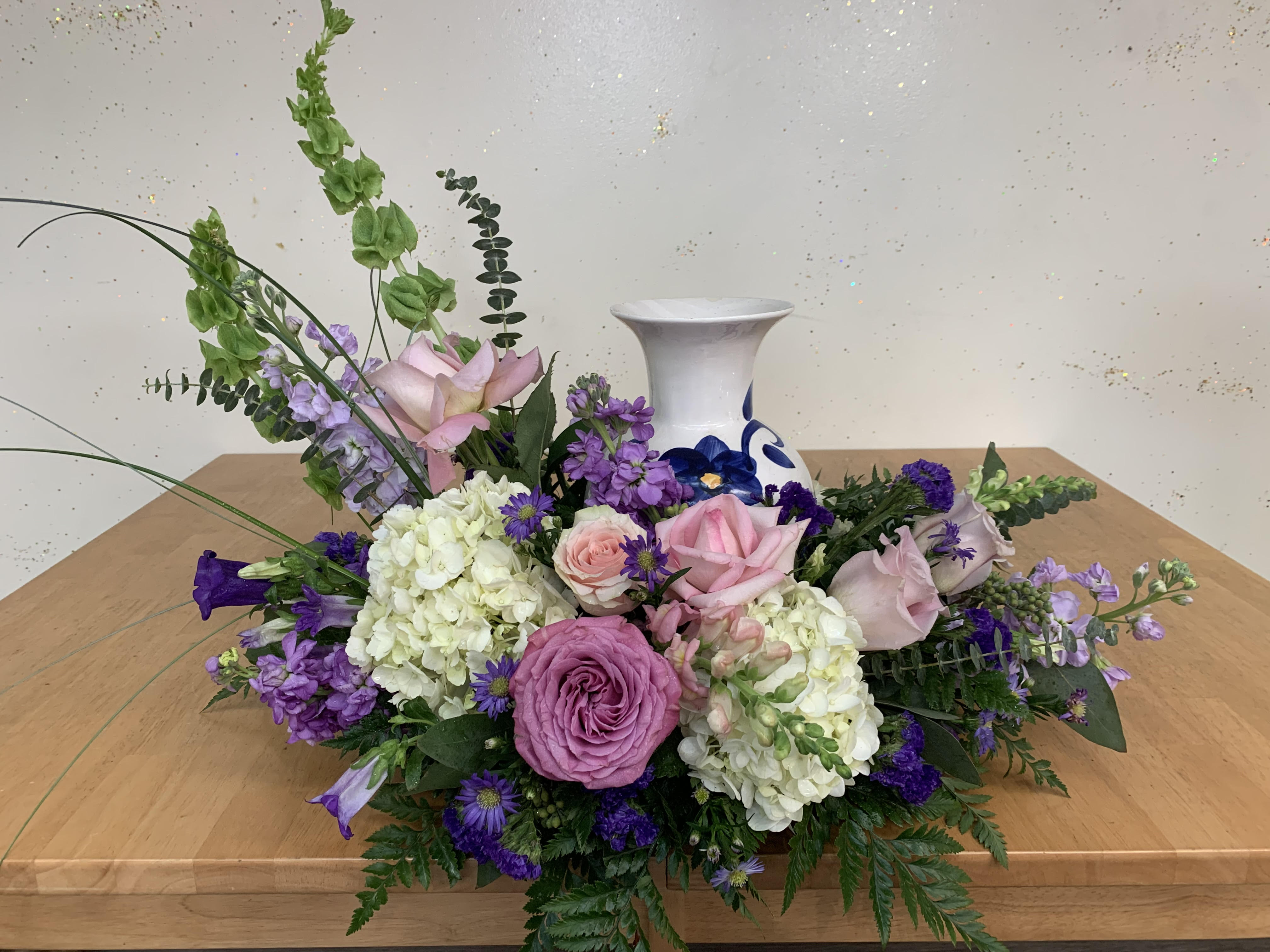 Low floral arrangement with pink and purple roses in a white vase