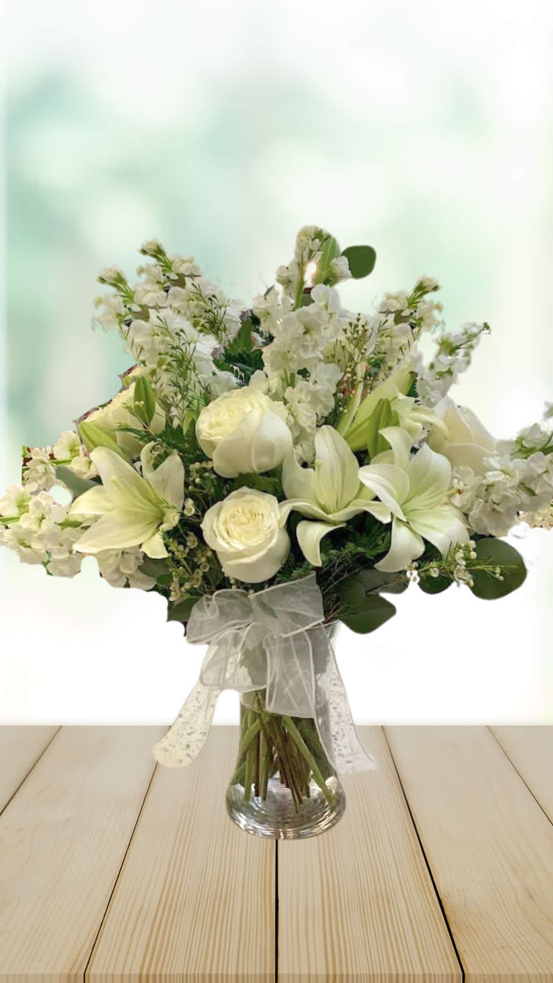 White floral bouquet in a clear glass vase with a sheer ribbon