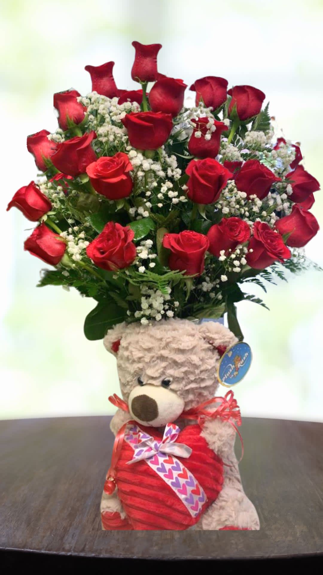 Red roses arranged in a teddy bear container with a heart ribbon