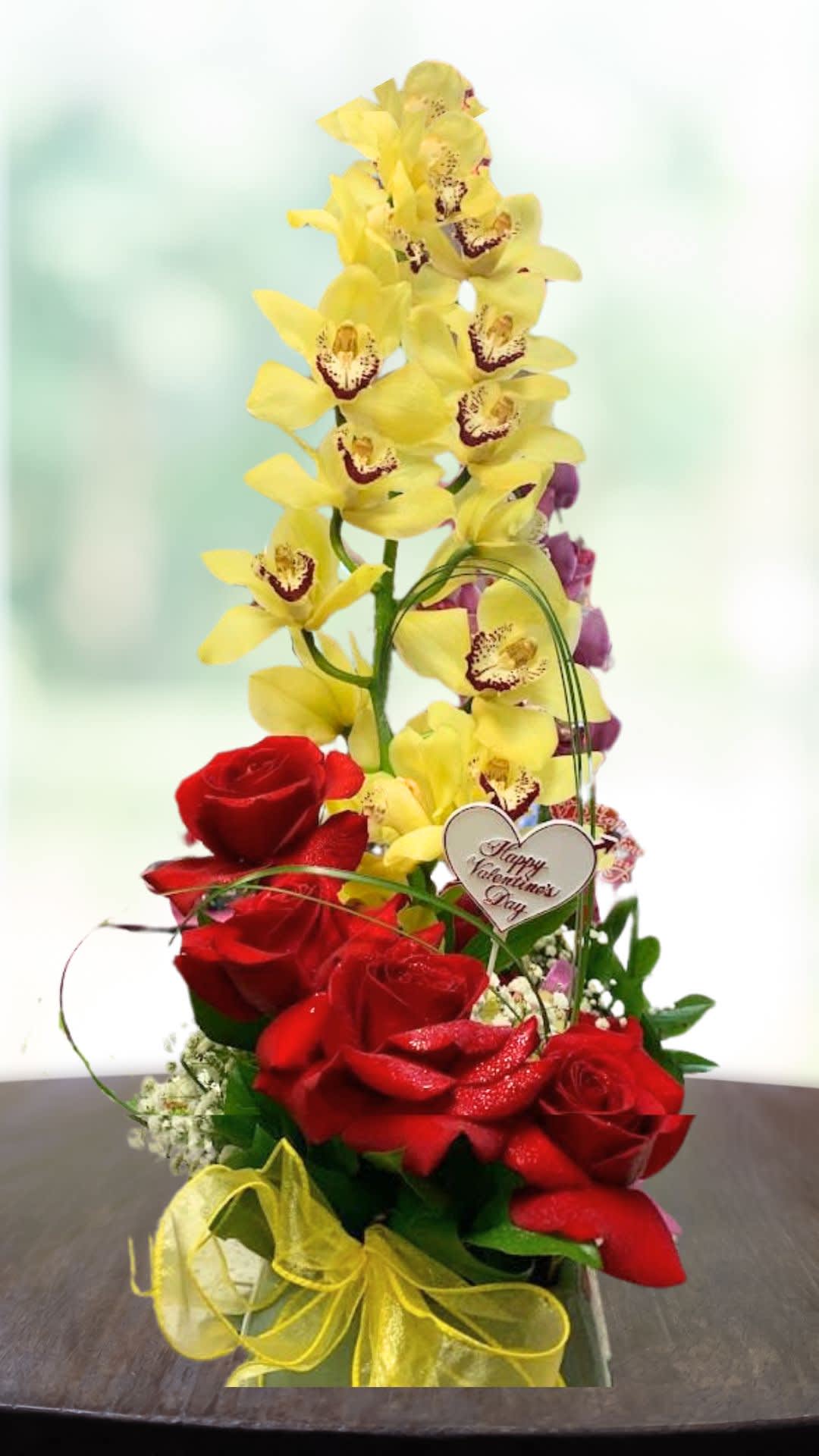 Red roses with tall yellow orchids and a Valentine heart pick