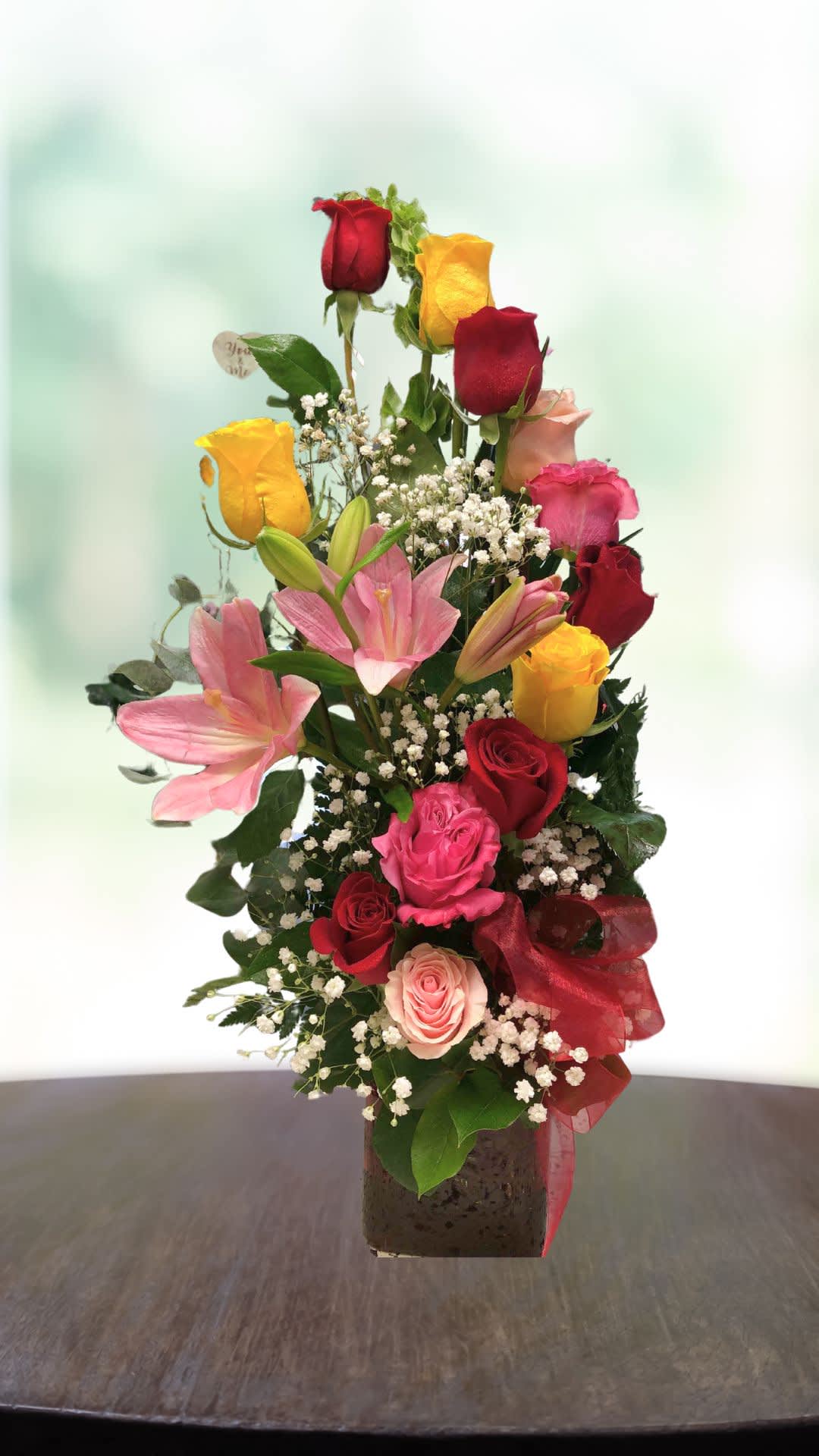 Mixed bouquet of roses and pink lilies in a square vase