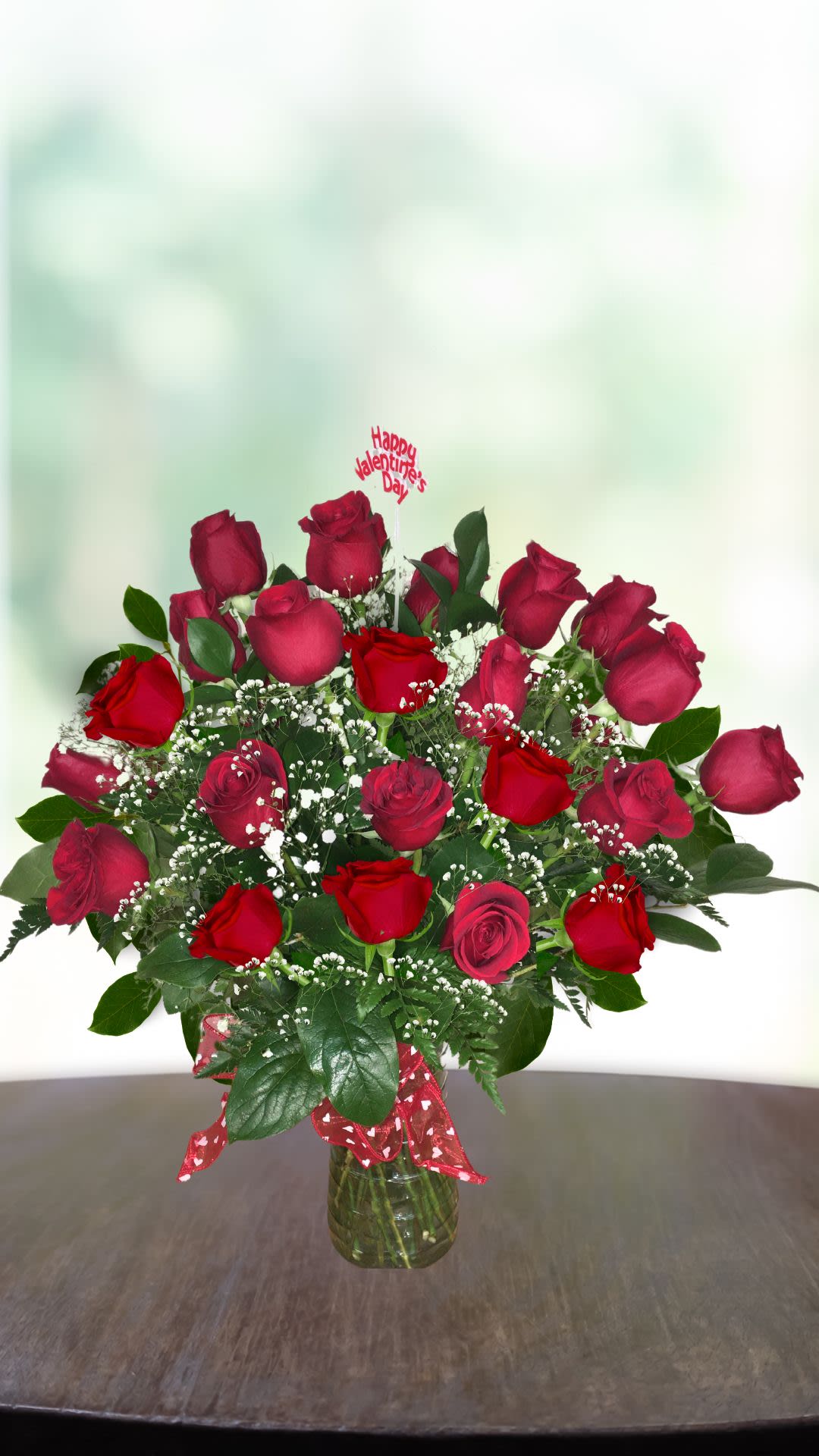 Bouquet of red roses in a glass vase with a Valentine topper