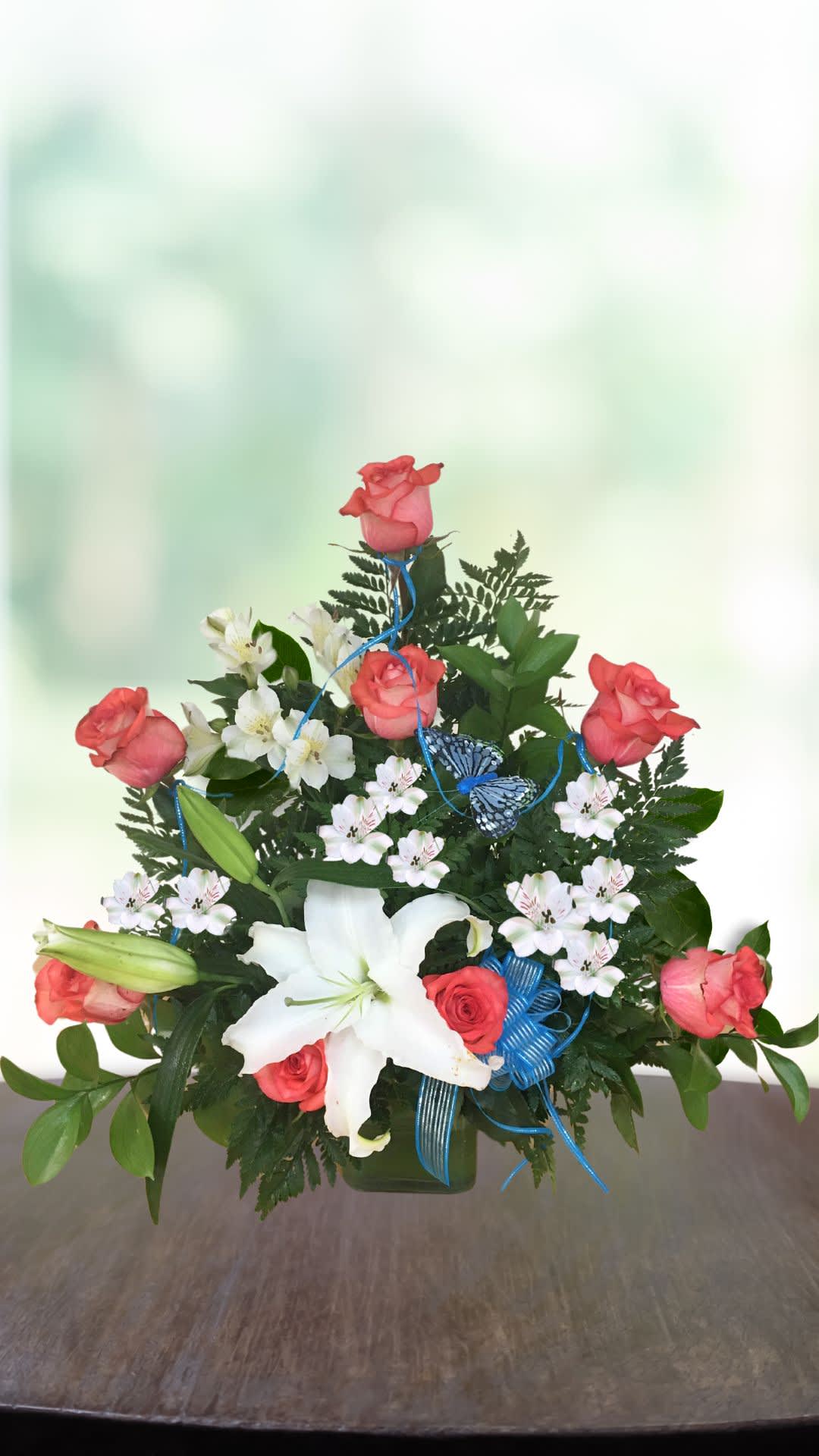 Pink roses and white lilies arranged in a green vase with blue ribbon and butterfly accents.