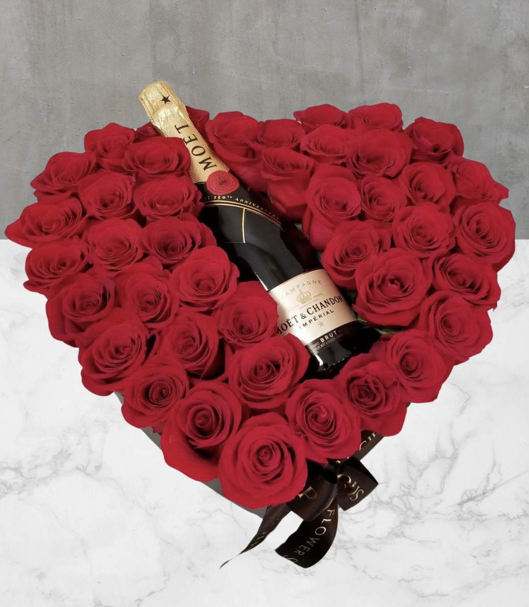 Heart-shaped bouquet of red roses with a champagne bottle in the center
