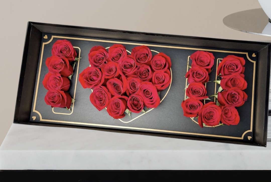 Red roses arranged to spell "I LOVE U" in a black tray