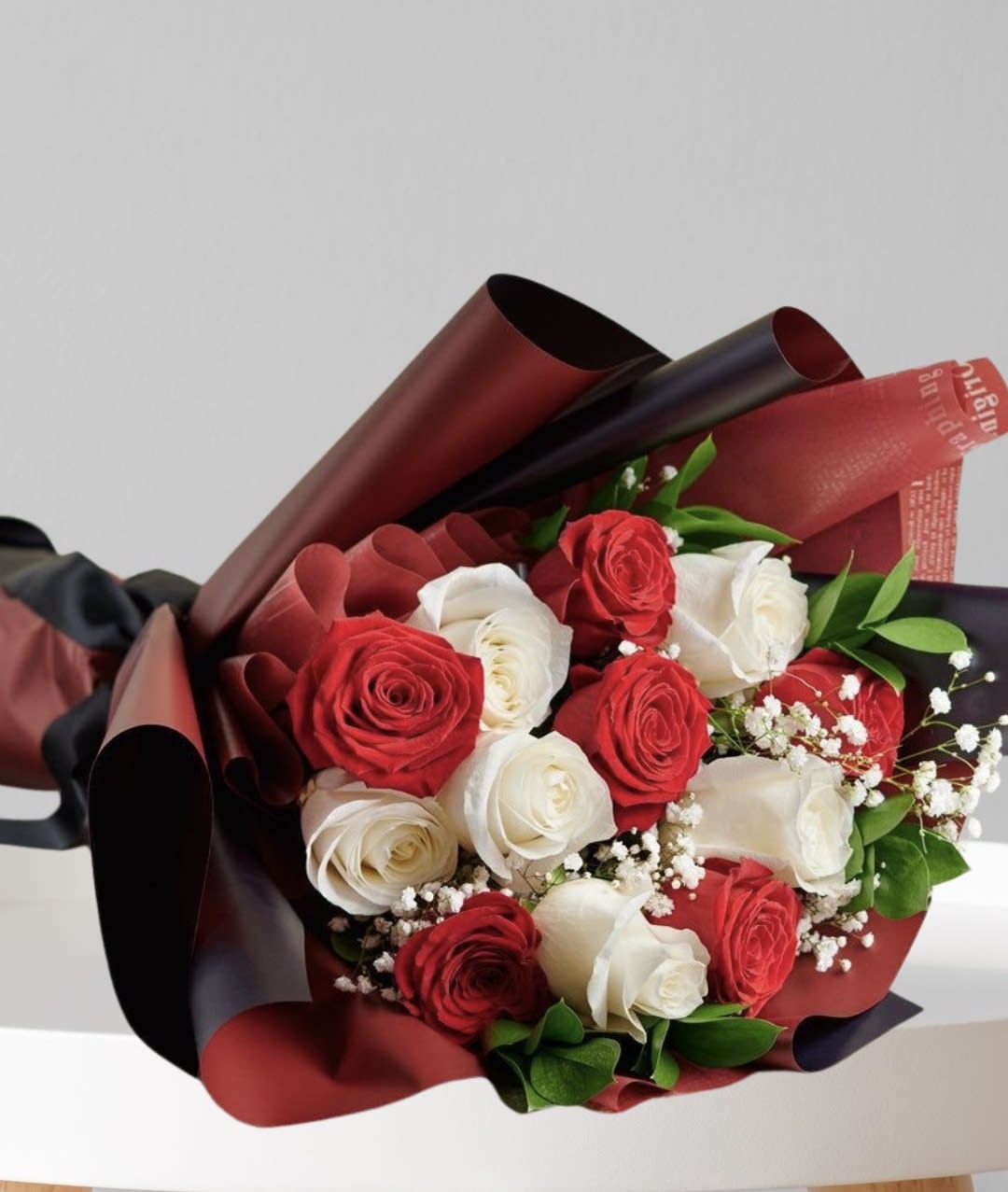 Bouquet of red and white roses wrapped in burgundy and black paper