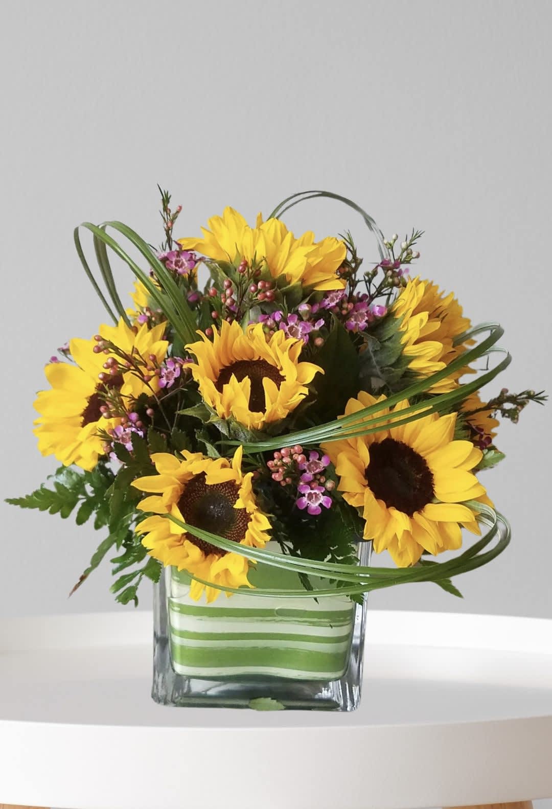 Sunflower bouquet in a square glass vase with pink filler flowers