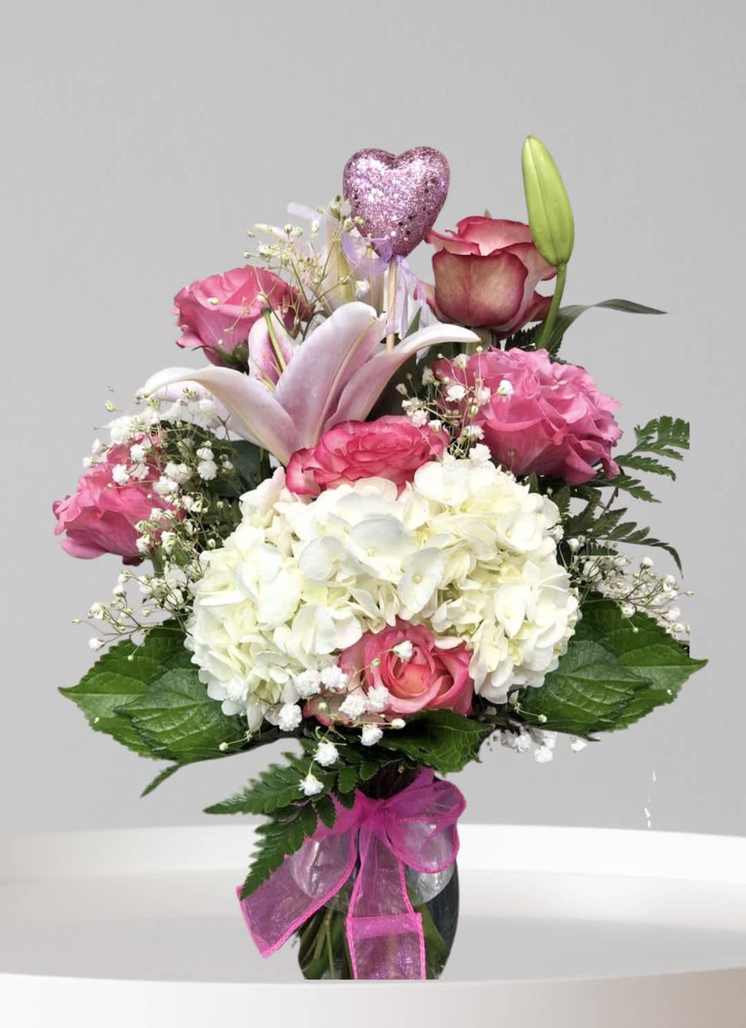 Pink and white bouquet with roses, hydrangea, and a lily in a vase