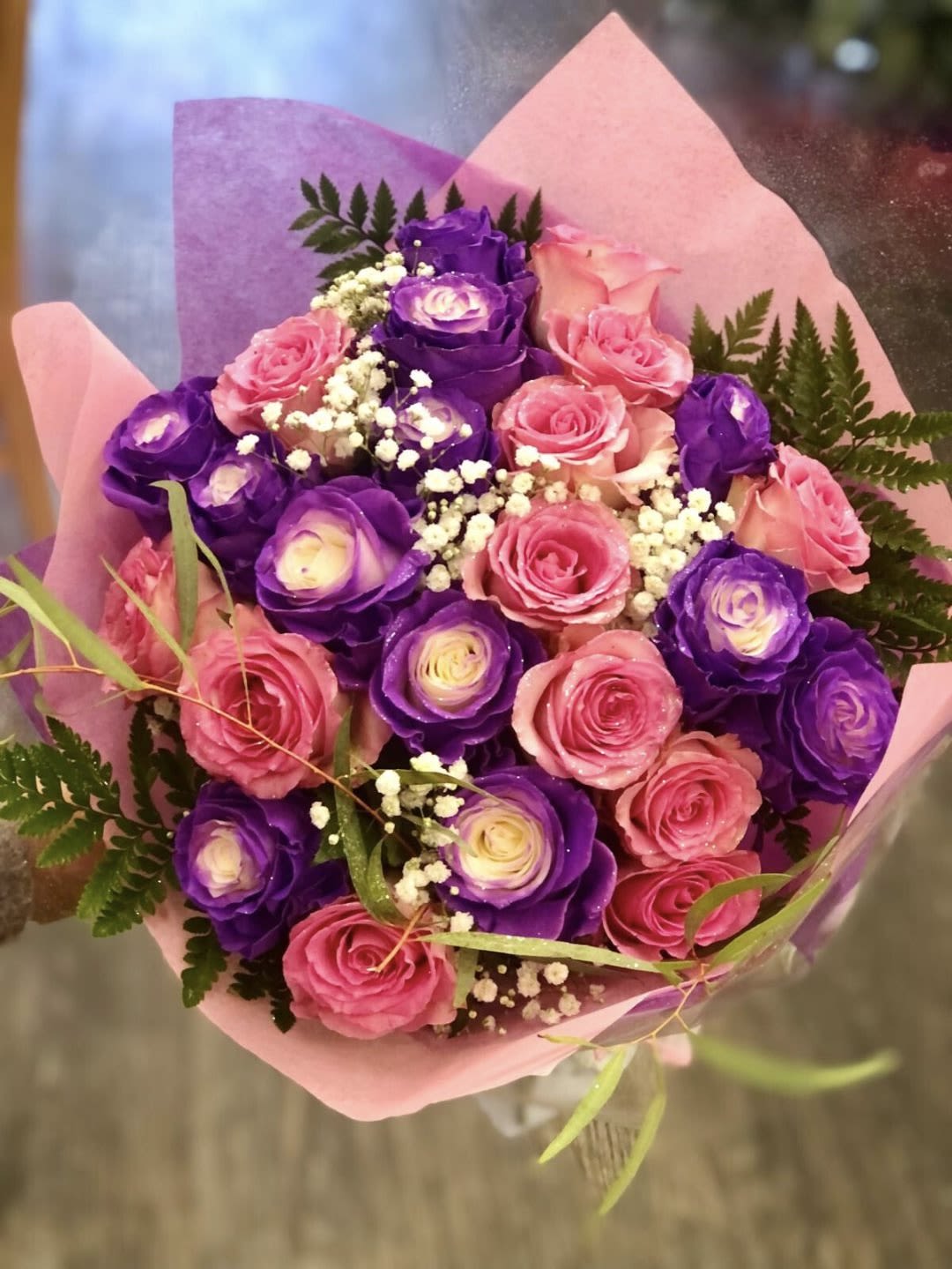 Bouquet of pink and purple roses wrapped in pink paper