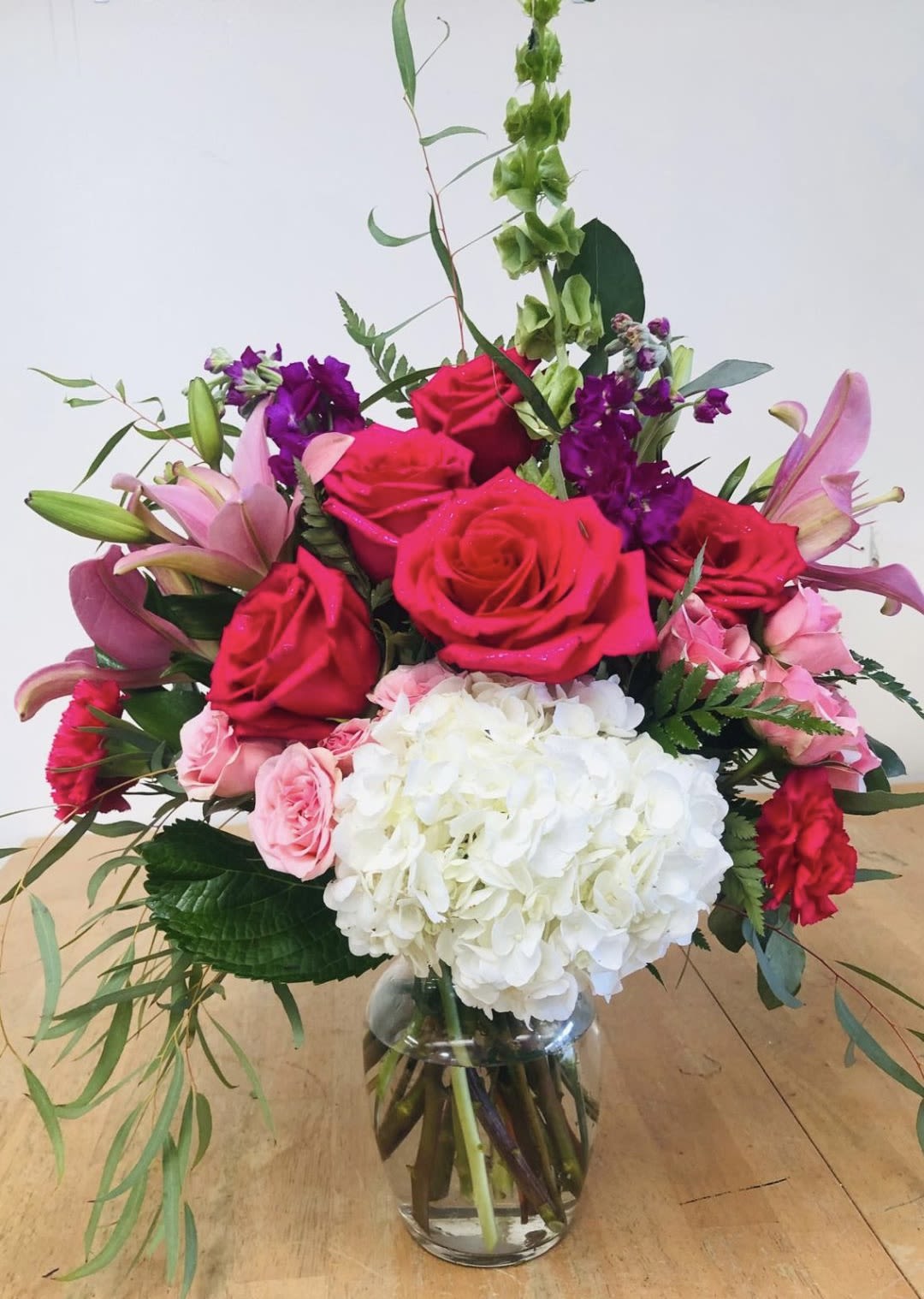 Bouquet of pink and red roses with white hydrangea in a glass vase