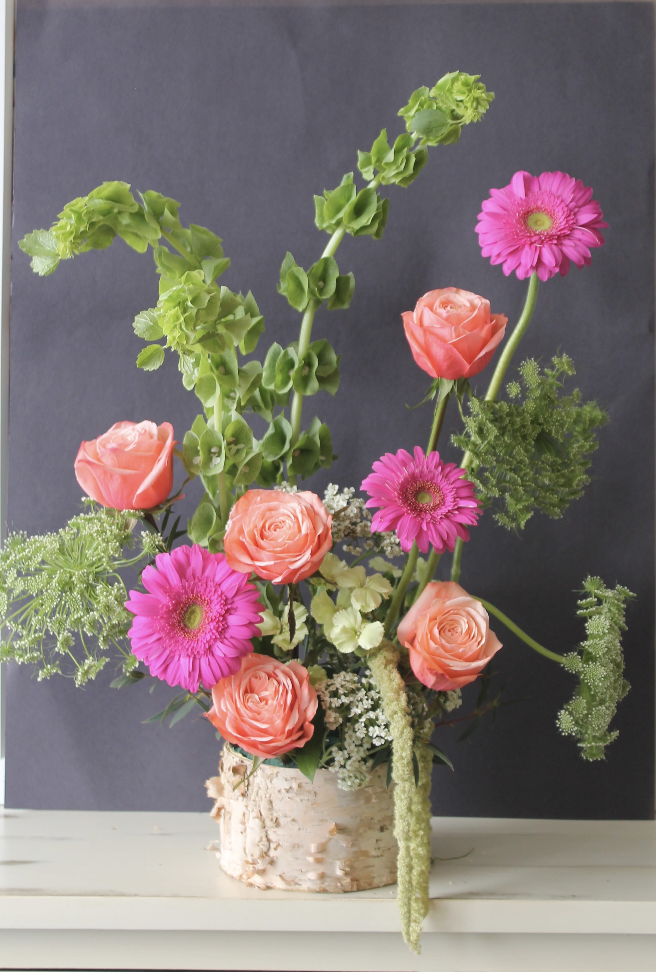 Pink roses and gerbera daisies in a birch bark container
