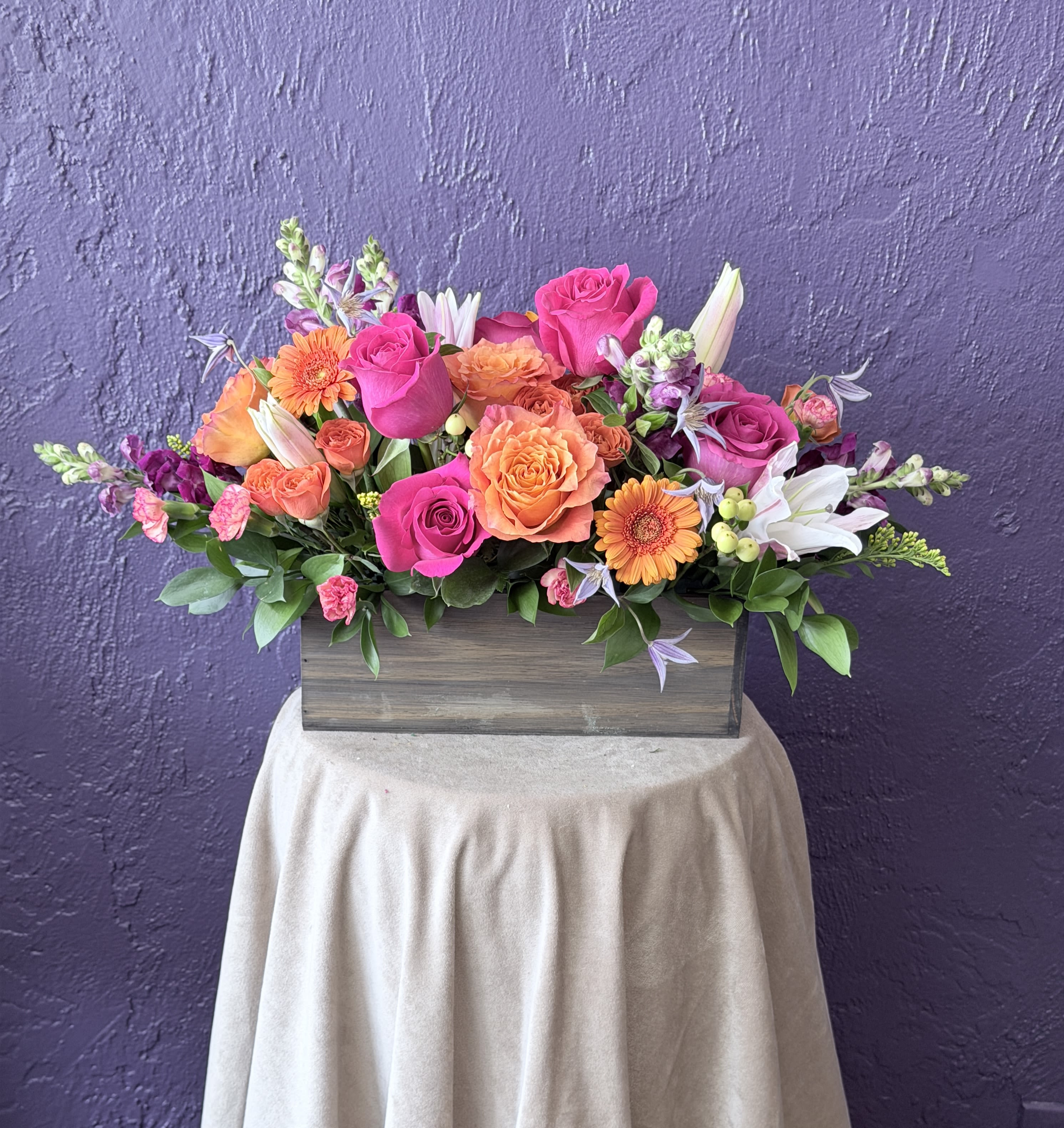 Mixed pink and orange flower arrangement in a wooden box