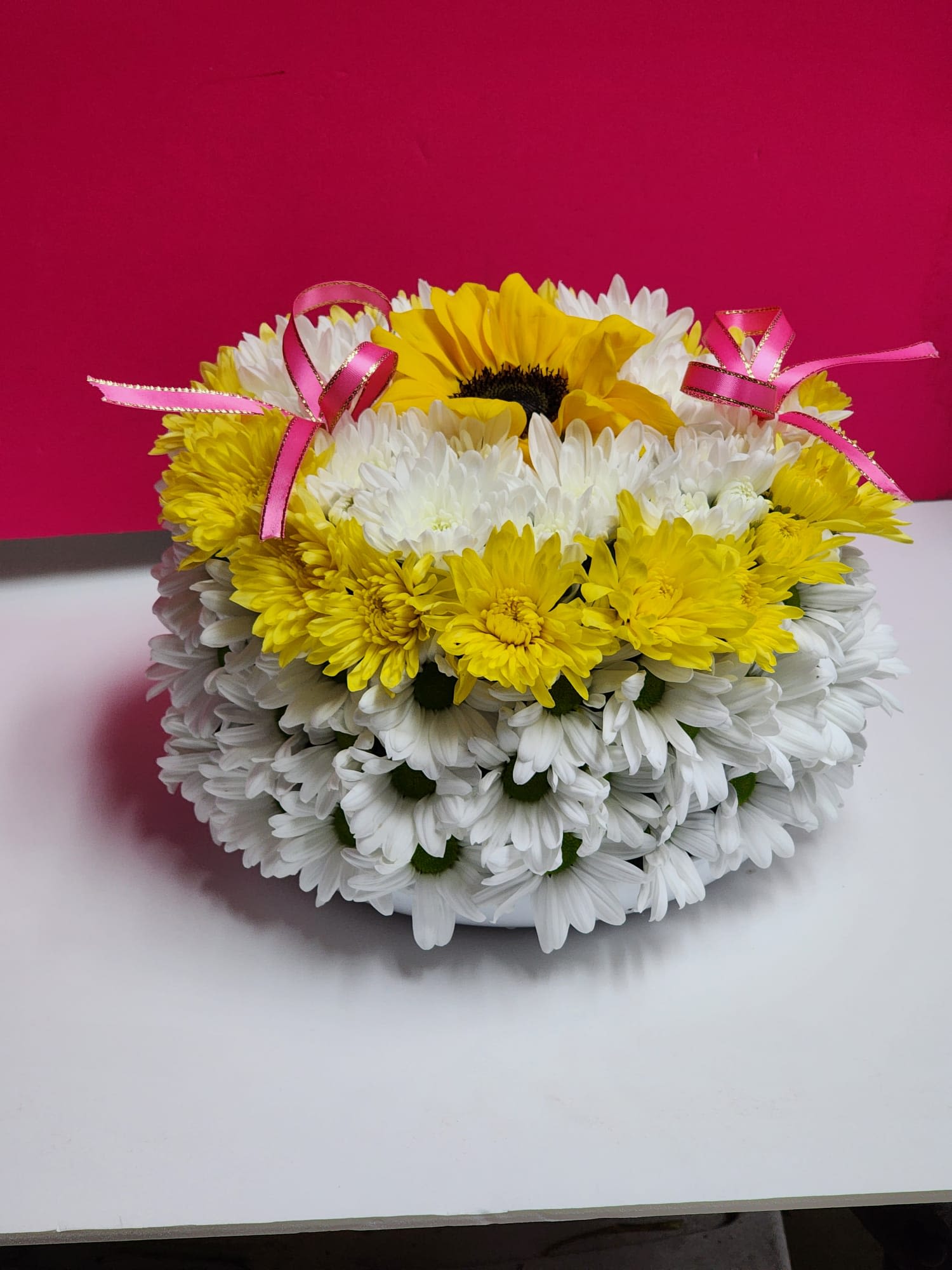Round bouquet of white and yellow daisies with pink ribbon bows