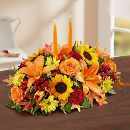 Autumn floral centerpiece with orange candles and mixed blooms on a table