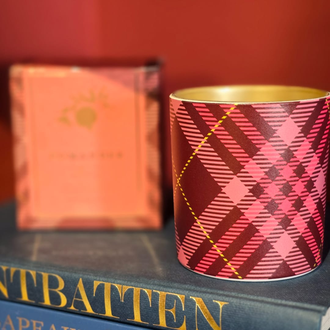 Patterned candle tin on stacked books with a blurred box behind it