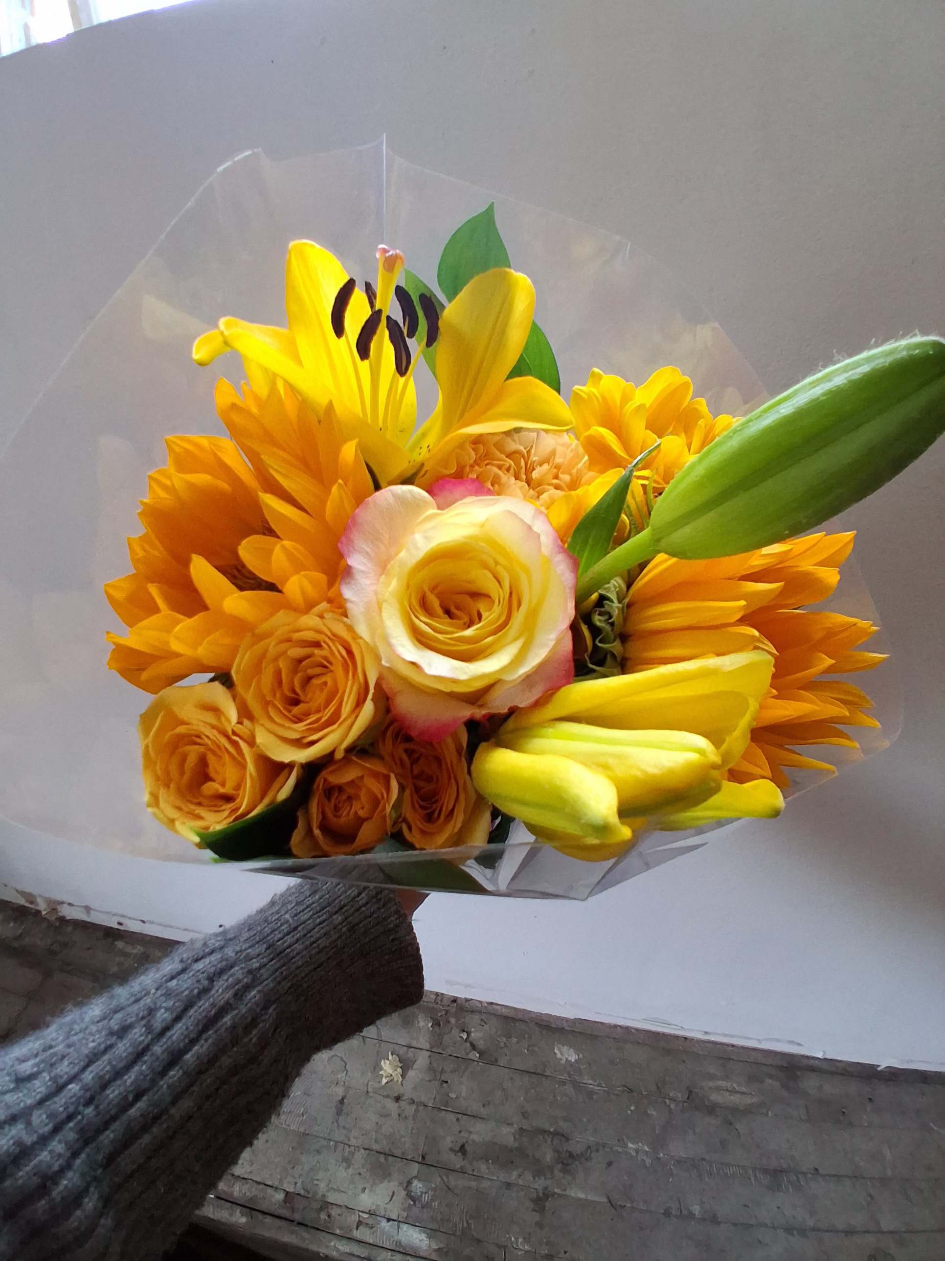 Yellow and orange bouquet with roses and lilies wrapped in clear plastic
