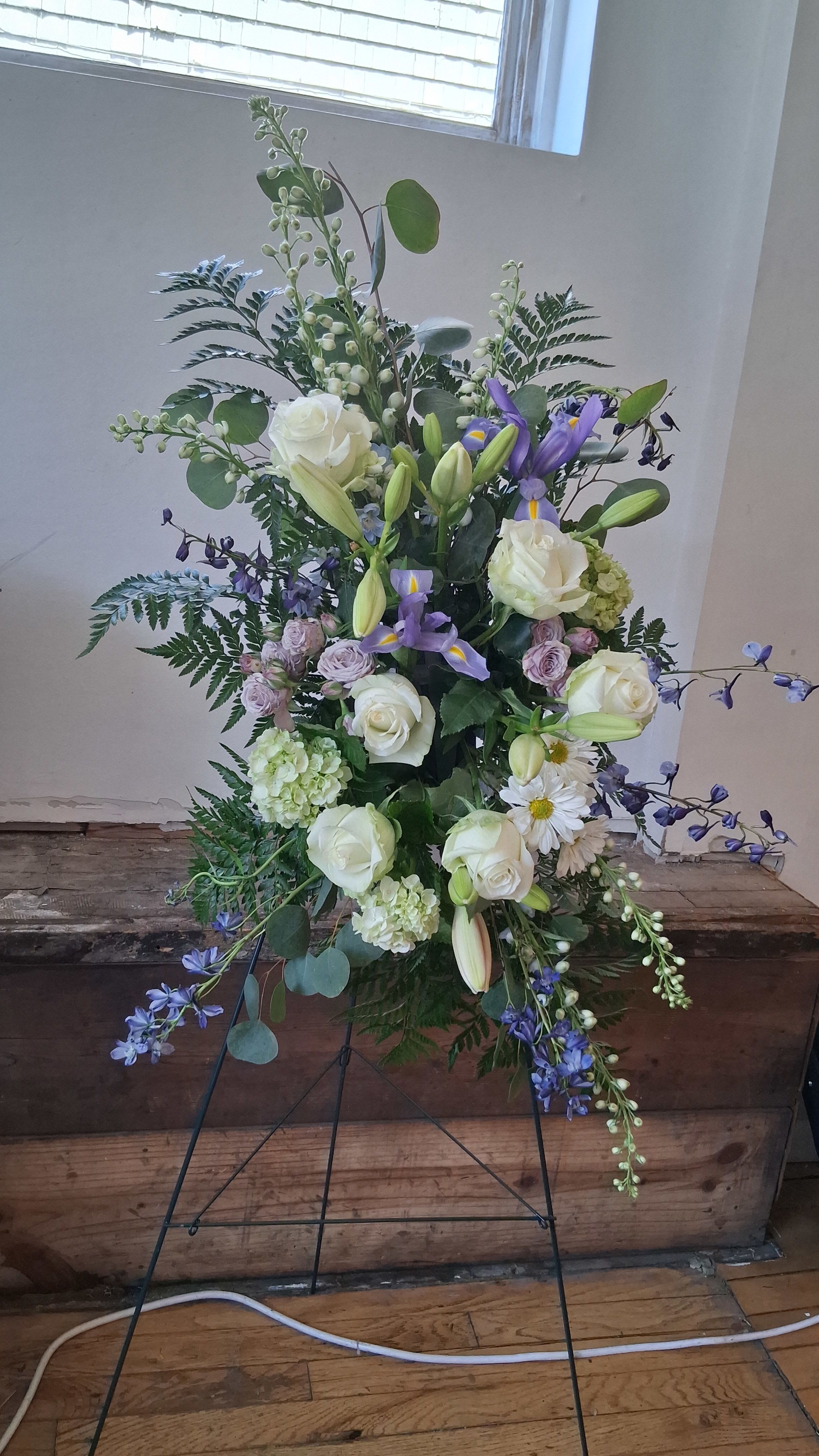 "Ocean breeze" standing spray  - A serene standing spray inspired by soft ocean colors, featuring white blooms, cool greens, and gentle touches of lavender for a peaceful, elegant tribute.