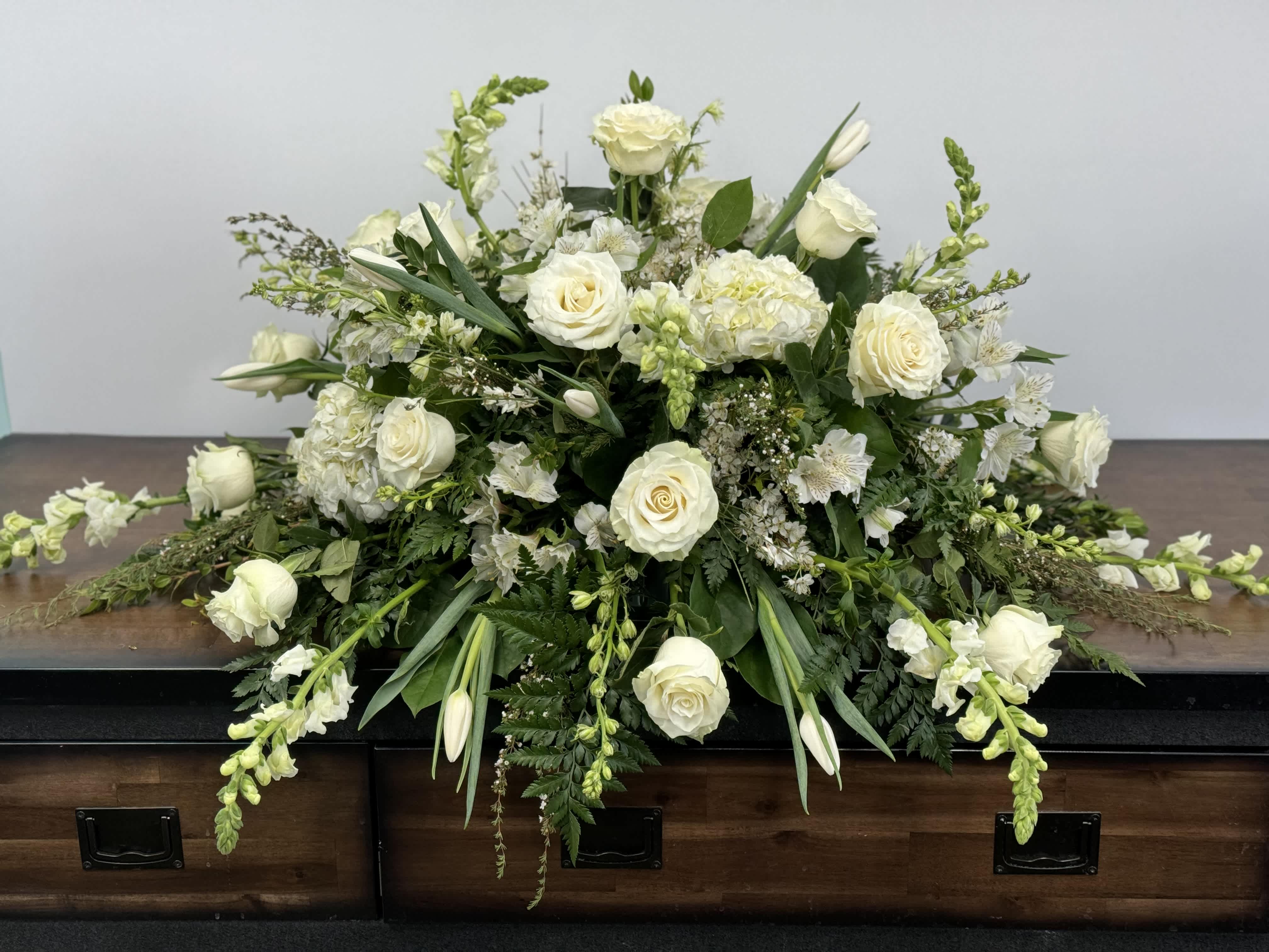 White floral casket spray with roses and lilies