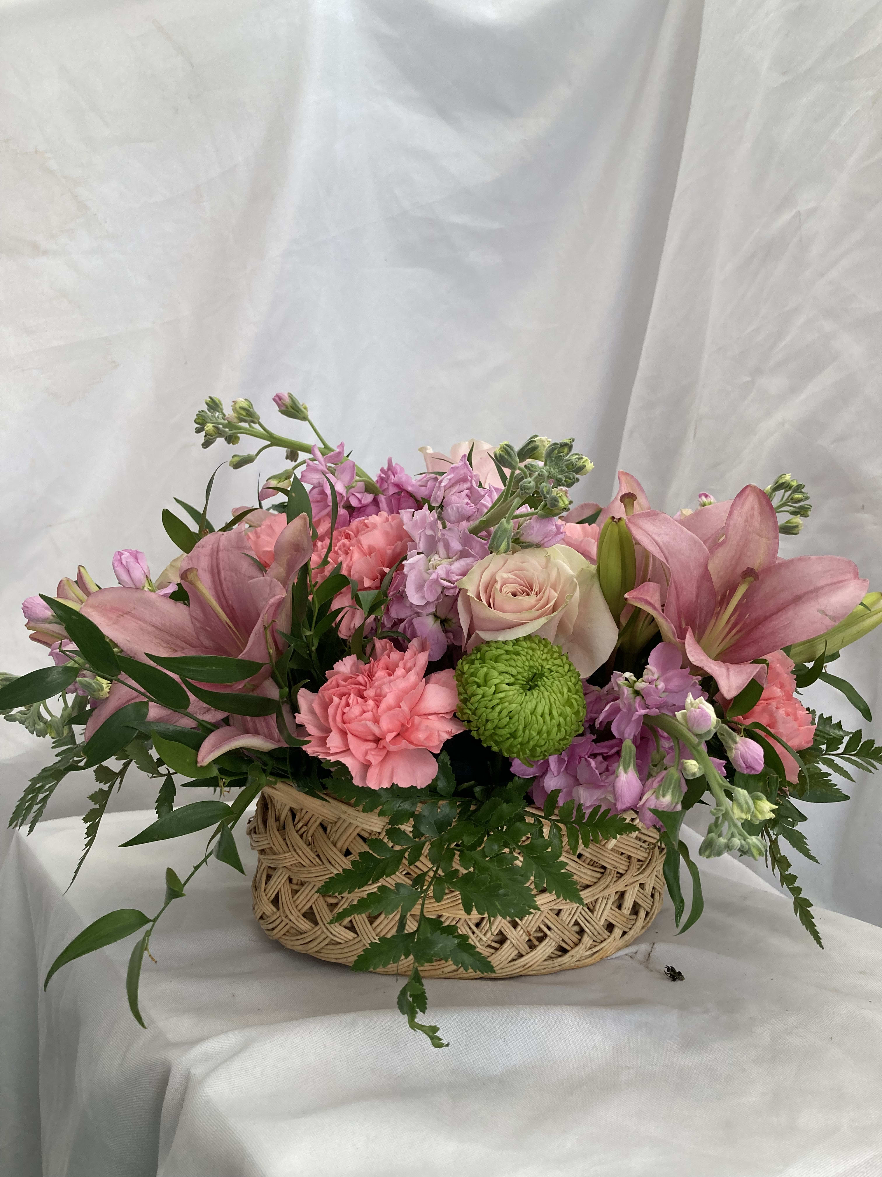 Pink lilies, roses, and carnations in a woven basket