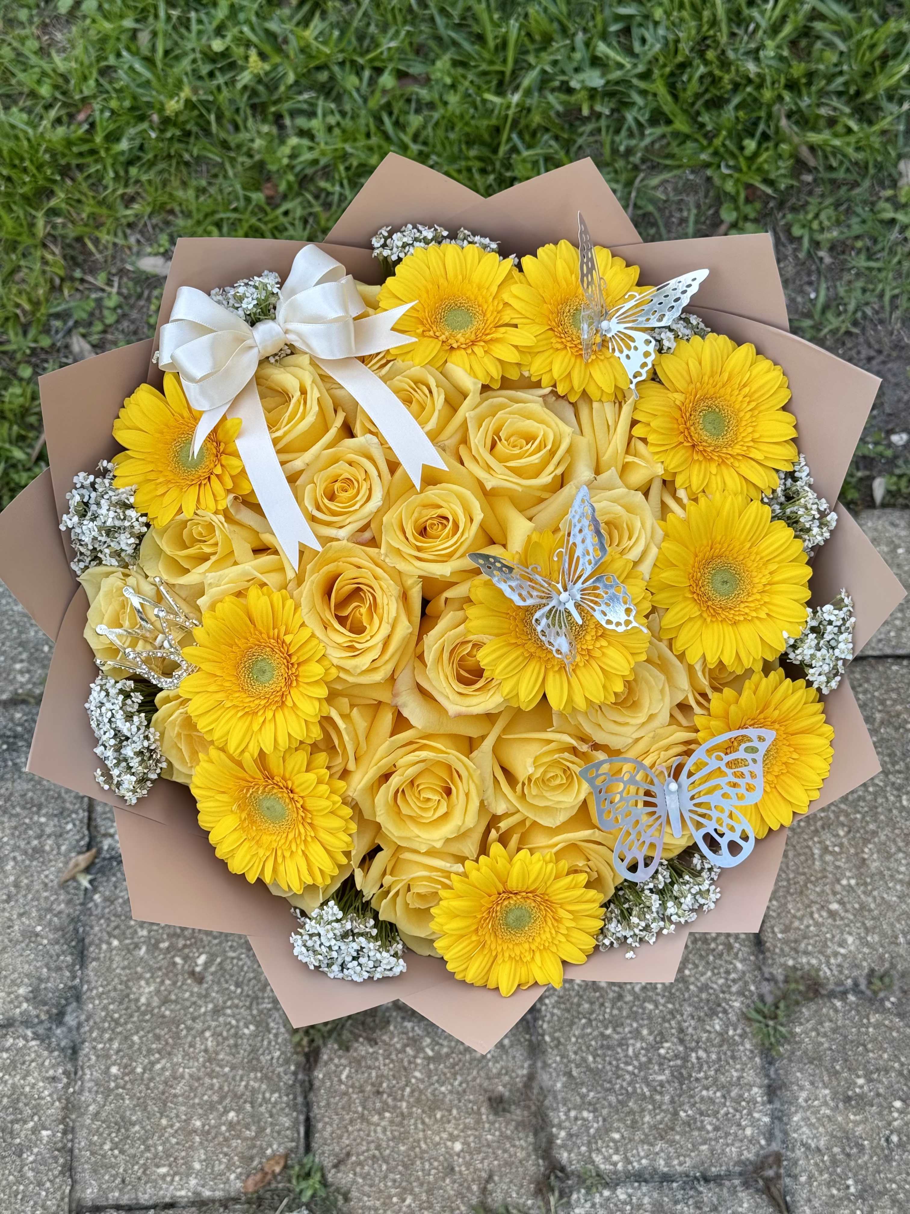 Butter Yellow - A bright, feel-good bouquet made to stand out. Butter Yellow features a 25 count of sunny yellow roses, vibrant gerbera daisies, soft white accents, and delicate butterfly detail for a look that feels fresh, playful, and instantly uplifting. 