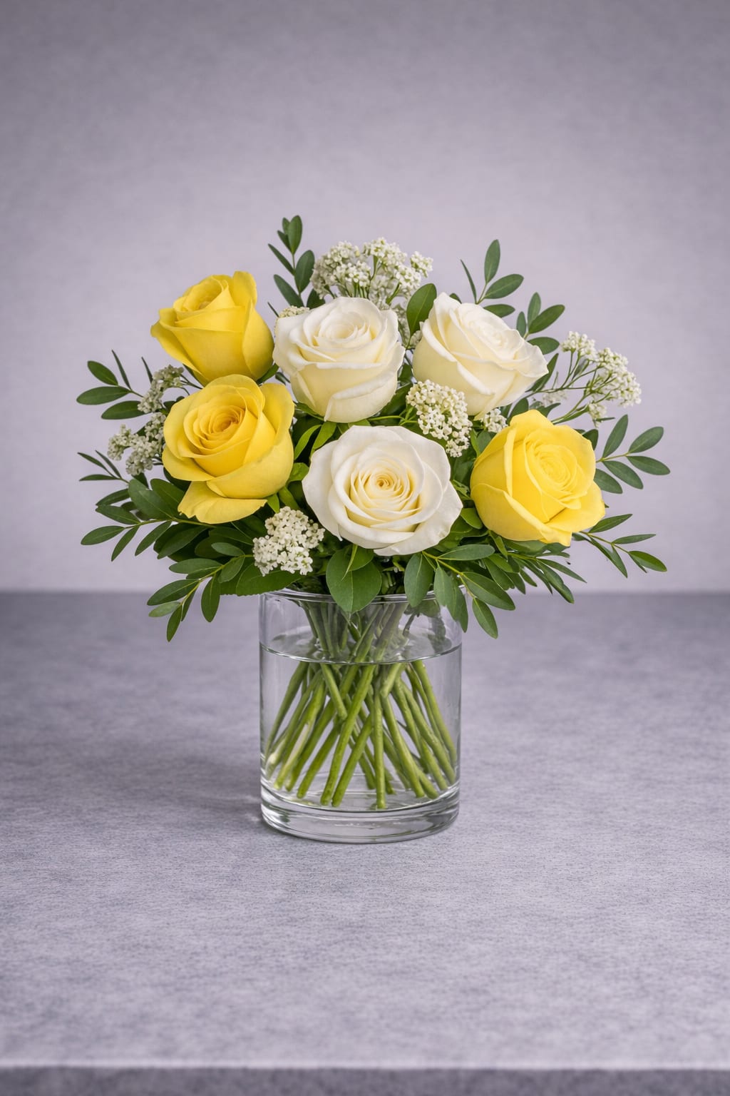 Yellow and white roses arranged in a clear glass vase