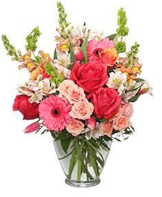 Mixed bouquet of pink and red flowers in a clear glass vase