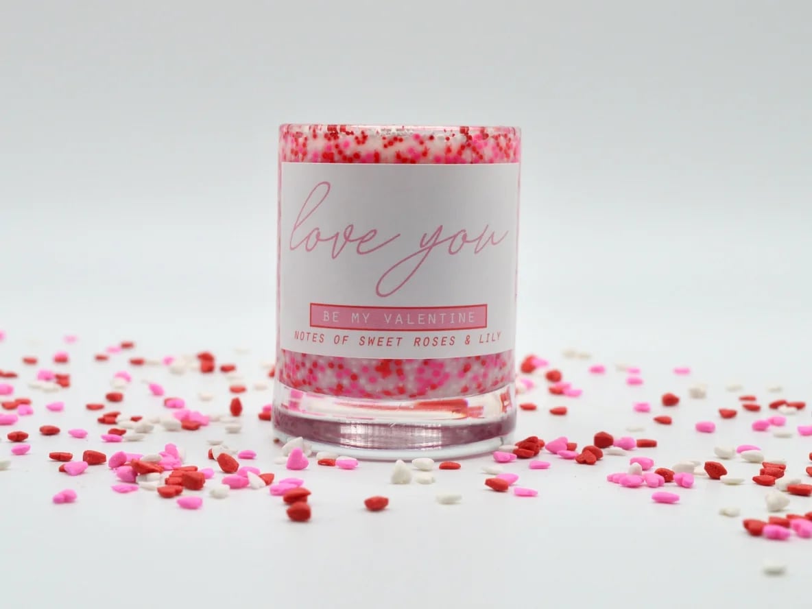 Pink candle in a glass jar with confetti around it