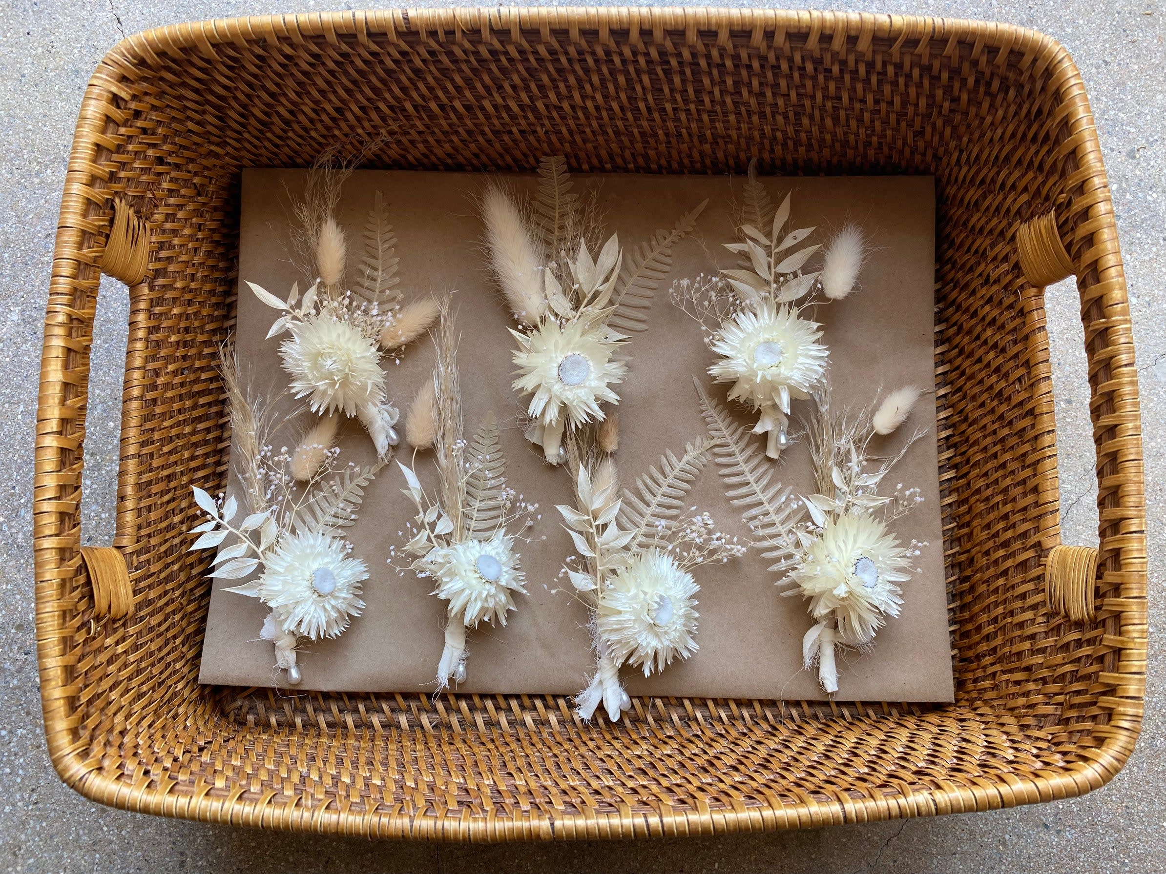 Basket of small dried floral boutonnieres in cream and beige tones