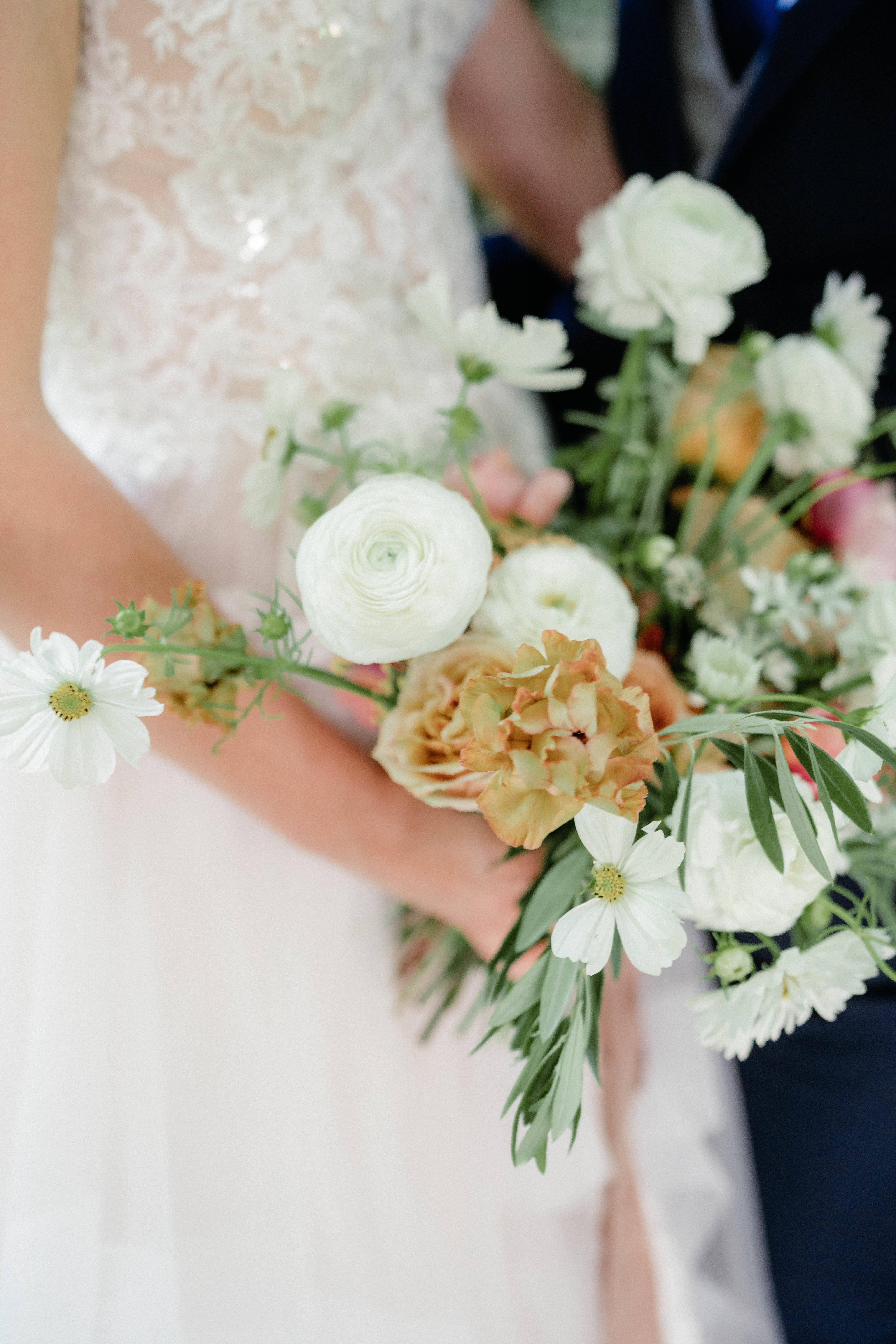 Bride holding a white and peach bouquet with daisy-like blooms