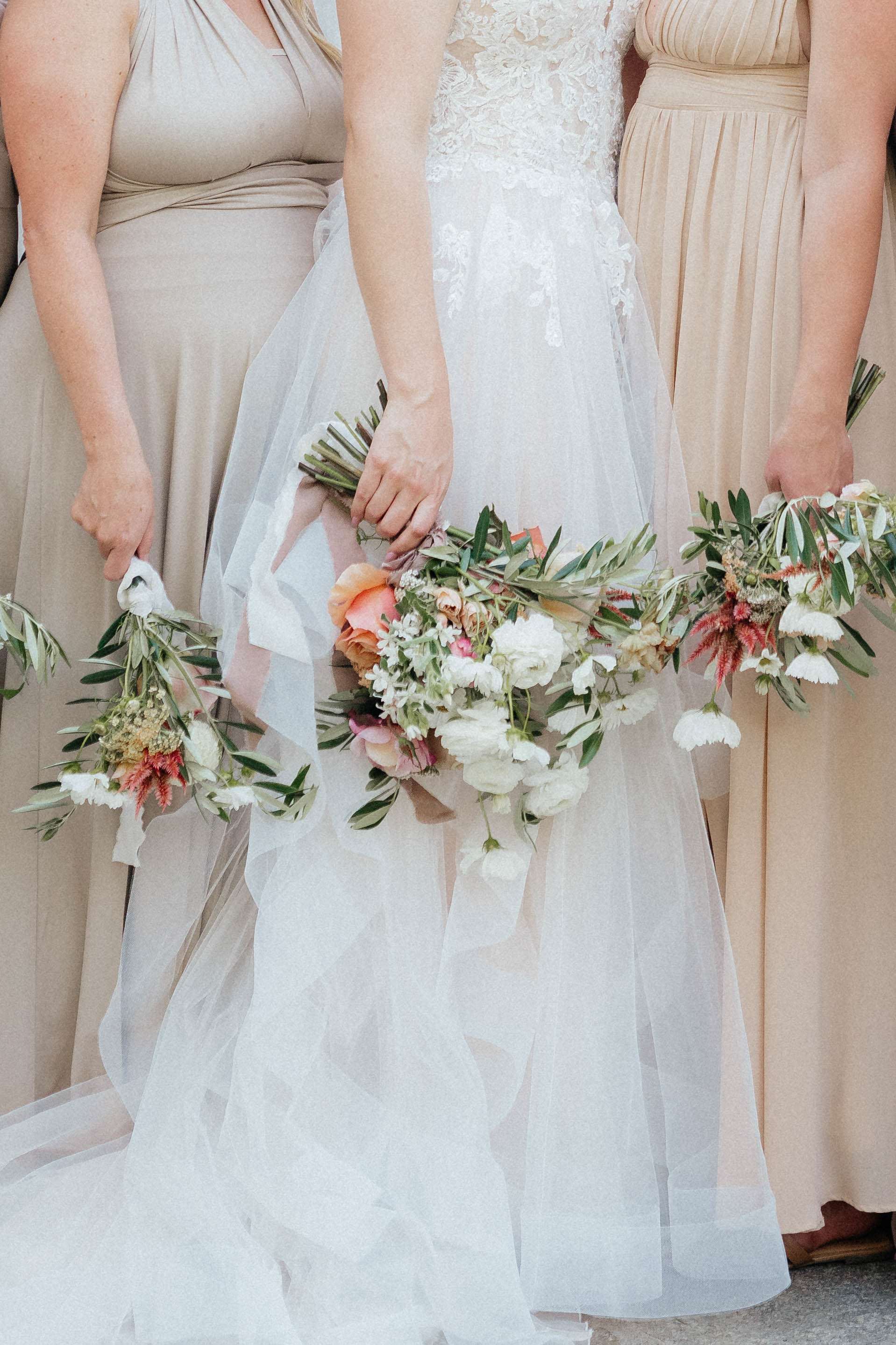 Bride and bridesmaids holding floral bouquets and wreaths