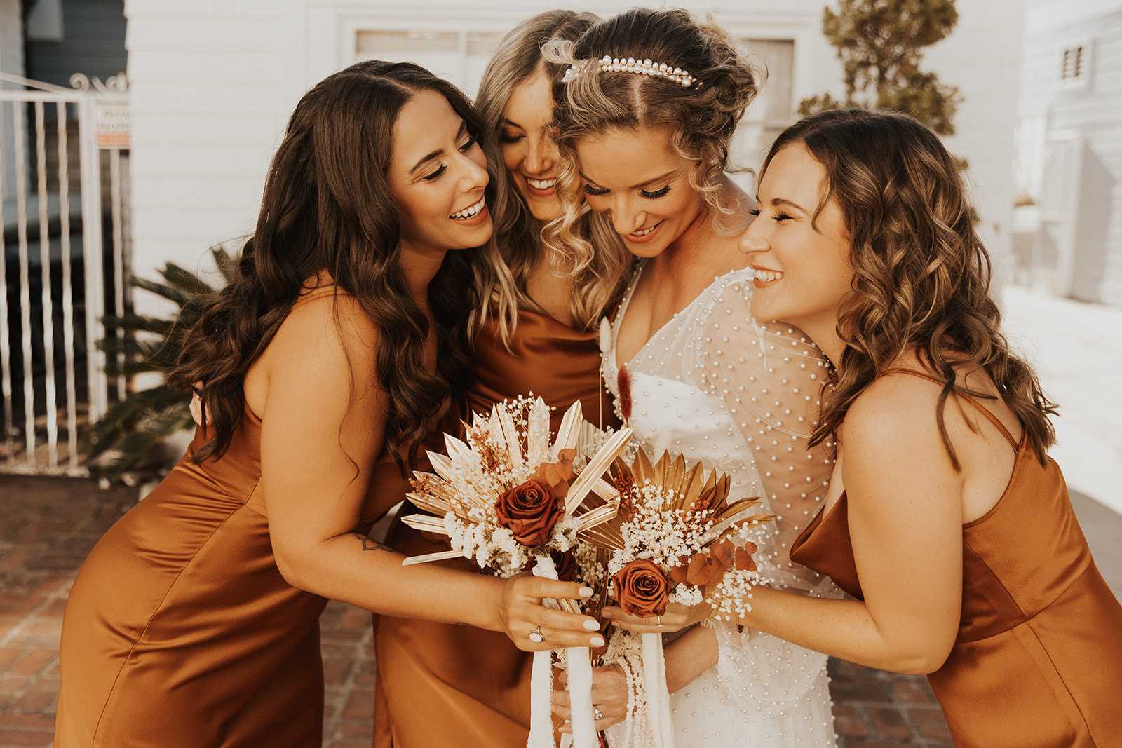 Bridesmaids and bride holding copper-toned bouquets with roses