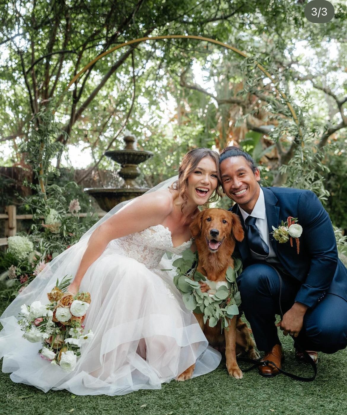 Bride and groom posing with a dog, each holding a floral bouquet