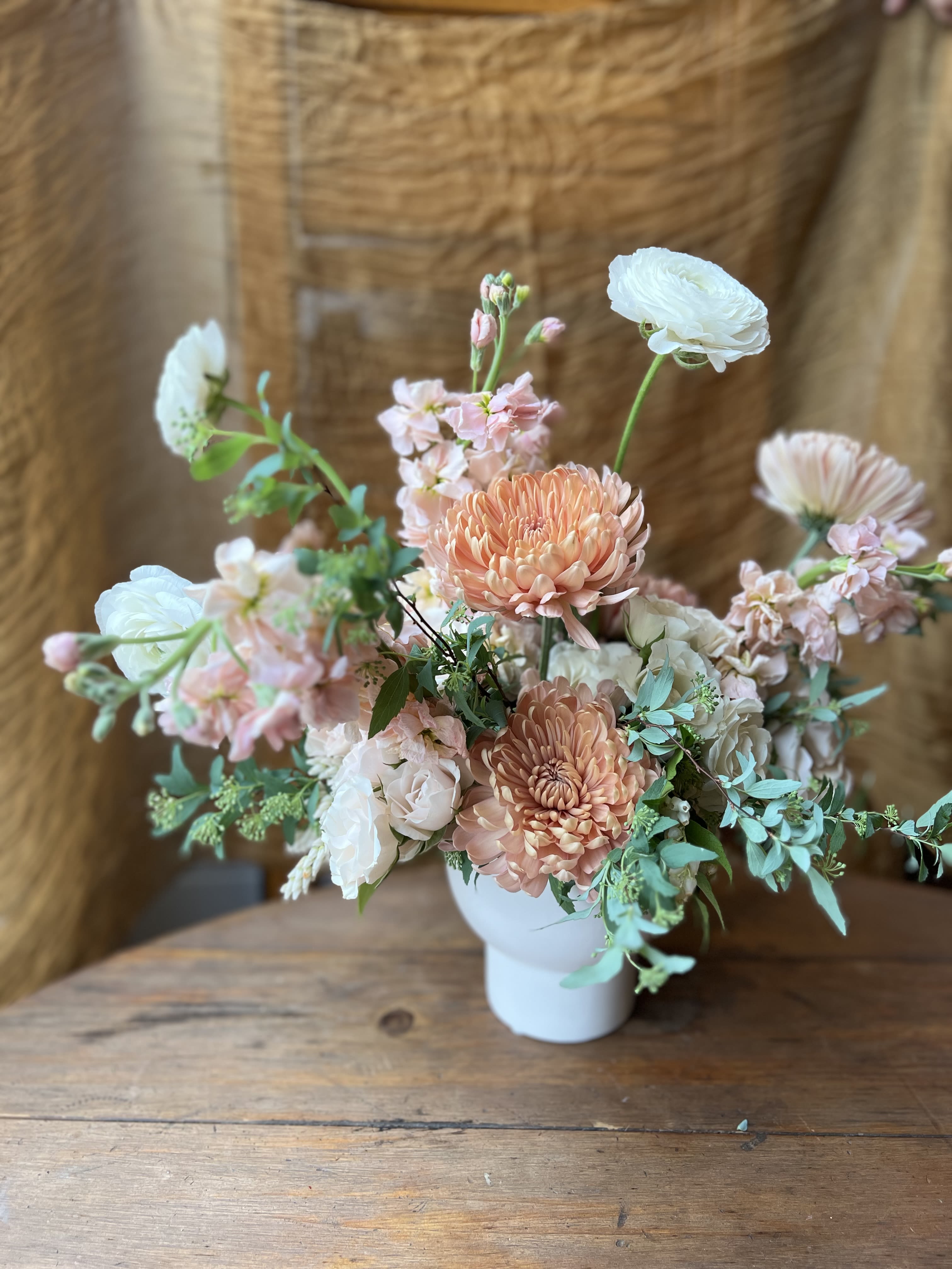 Peach and white floral arrangement in a white vase