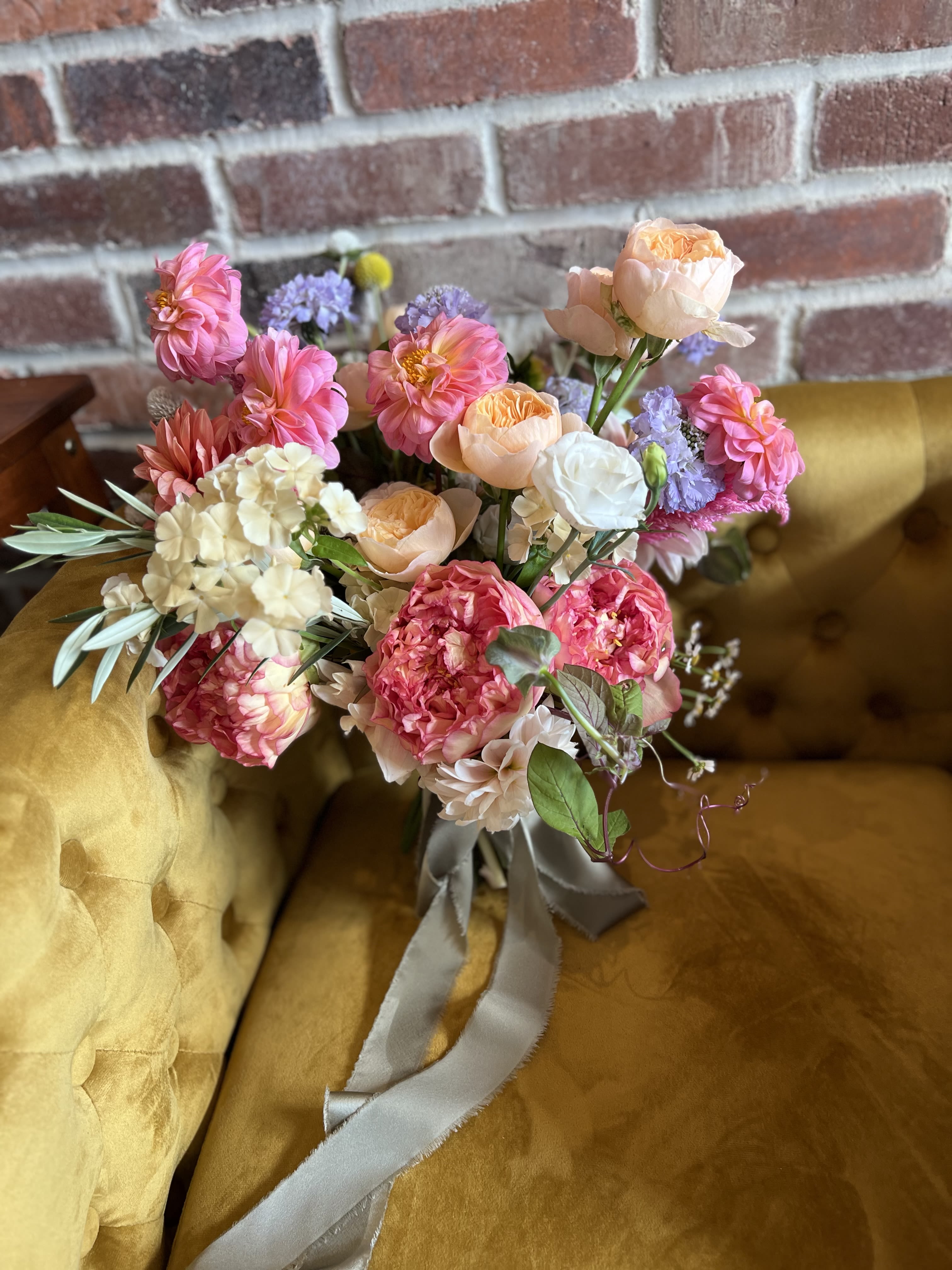 Bouquet of pink, peach, and white flowers tied with a gray ribbon