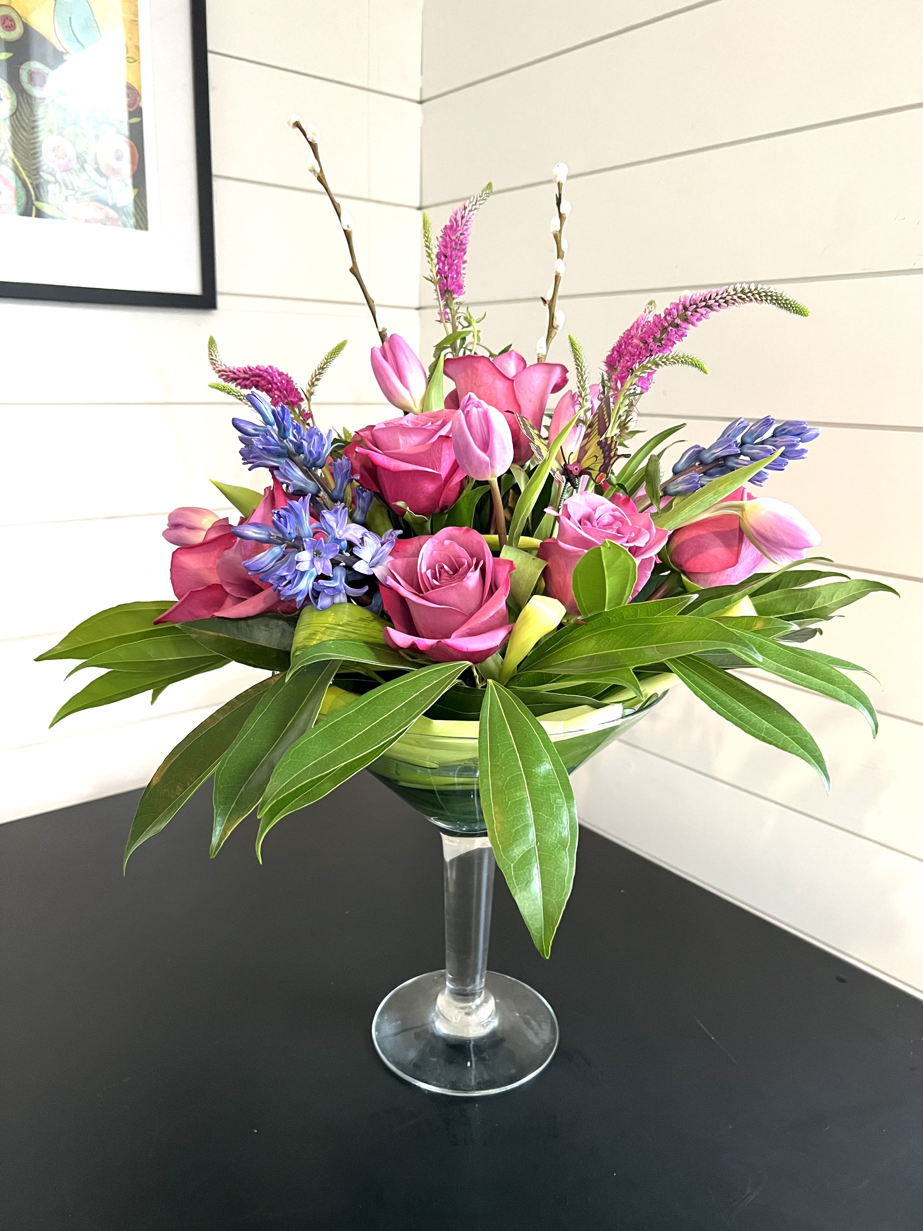 Pink roses and tulips arranged in a clear stemmed vase