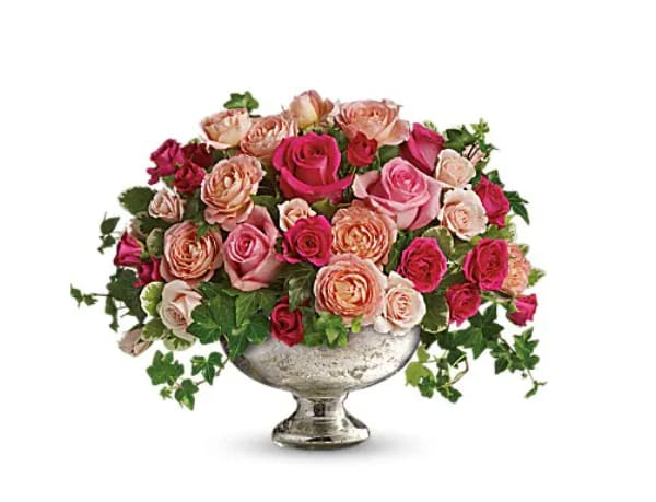 Pink and peach roses arranged in a silver pedestal vase