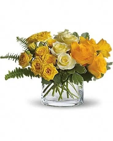 Yellow and white roses arranged in a clear glass vase